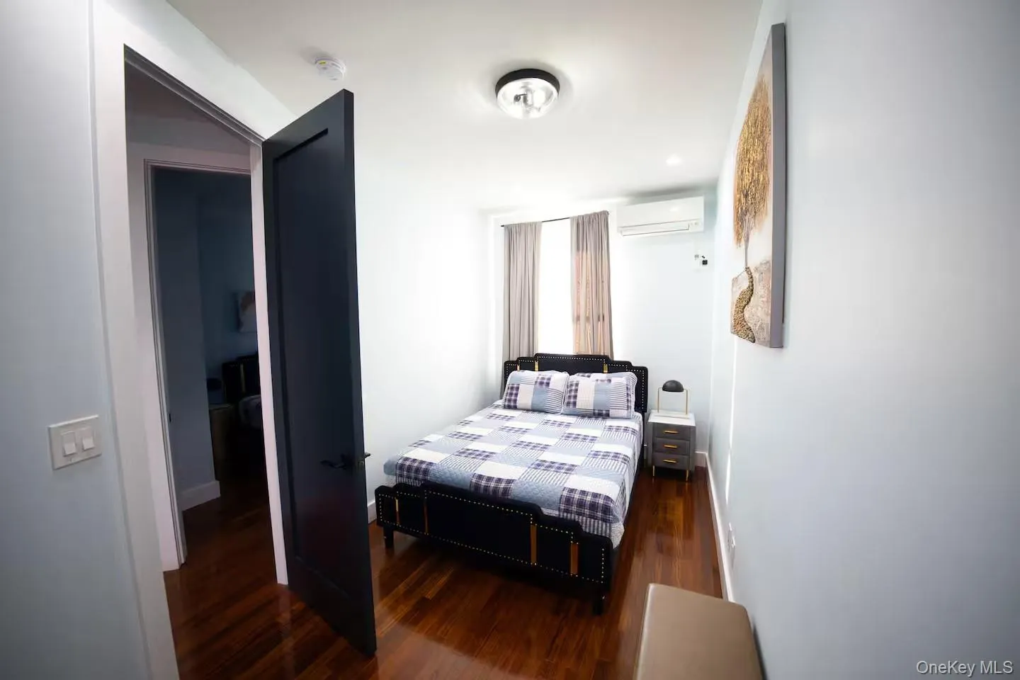 Bedroom with dark wood finished floors and a wall mounted air conditioner Bedroom with dark wood finished floors and a wall mounted air conditioner