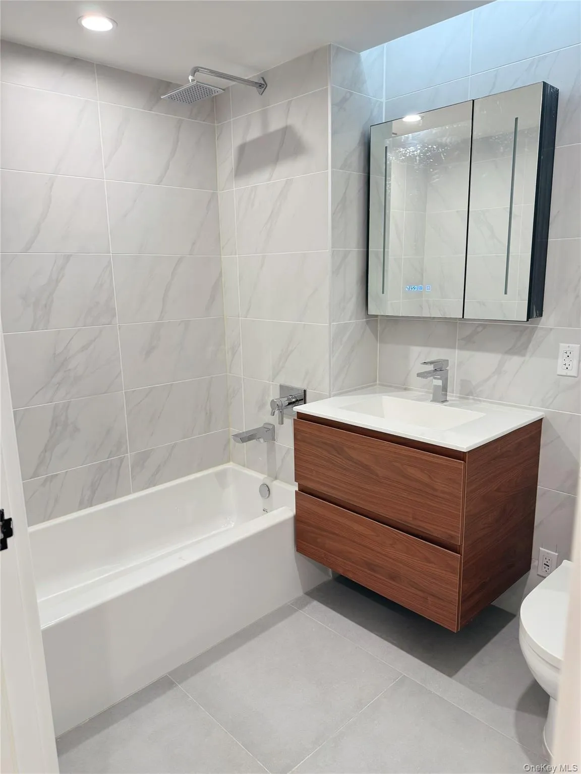 Bathroom featuring tile walls, vanity, bathtub / shower combination, and light tile patterned flooring Bathroom featuring tile walls, vanity, bathtub / shower combination, and light tile patterned flooring