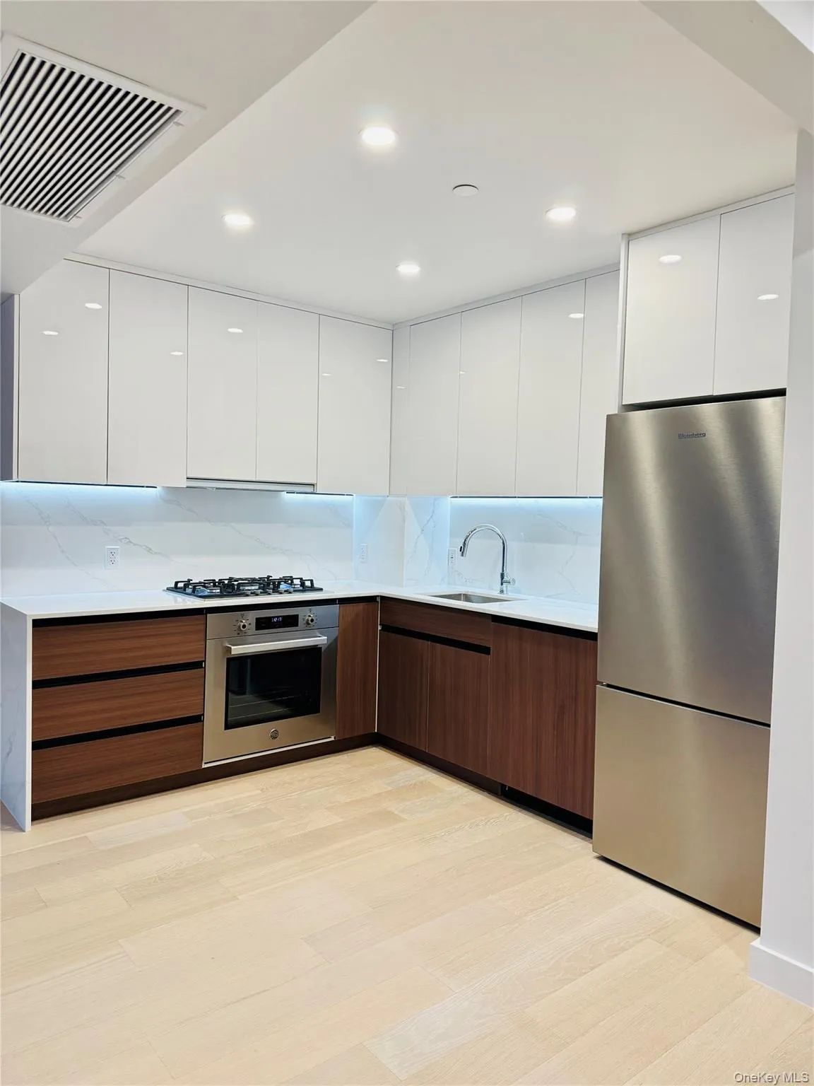 Kitchen with modern cabinets, white cabinets, appliances with stainless steel finishes, and recessed lighting Kitchen with modern cabinets, white cabinets, appliances with stainless steel finishes, and recessed lighting