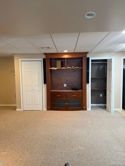 Finished basement with a paneled ceiling and carpet Finished basement with a paneled ceiling and carpet