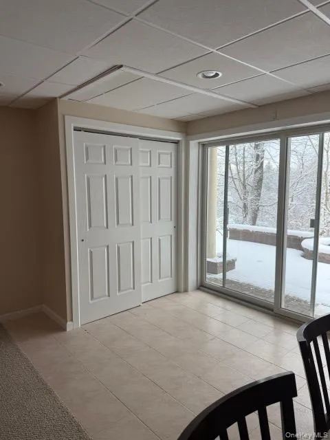 Unfurnished bedroom with a drop ceiling, a closet, and light tile patterned floors Unfurnished bedroom with a drop ceiling, a closet, and light tile patterned floors