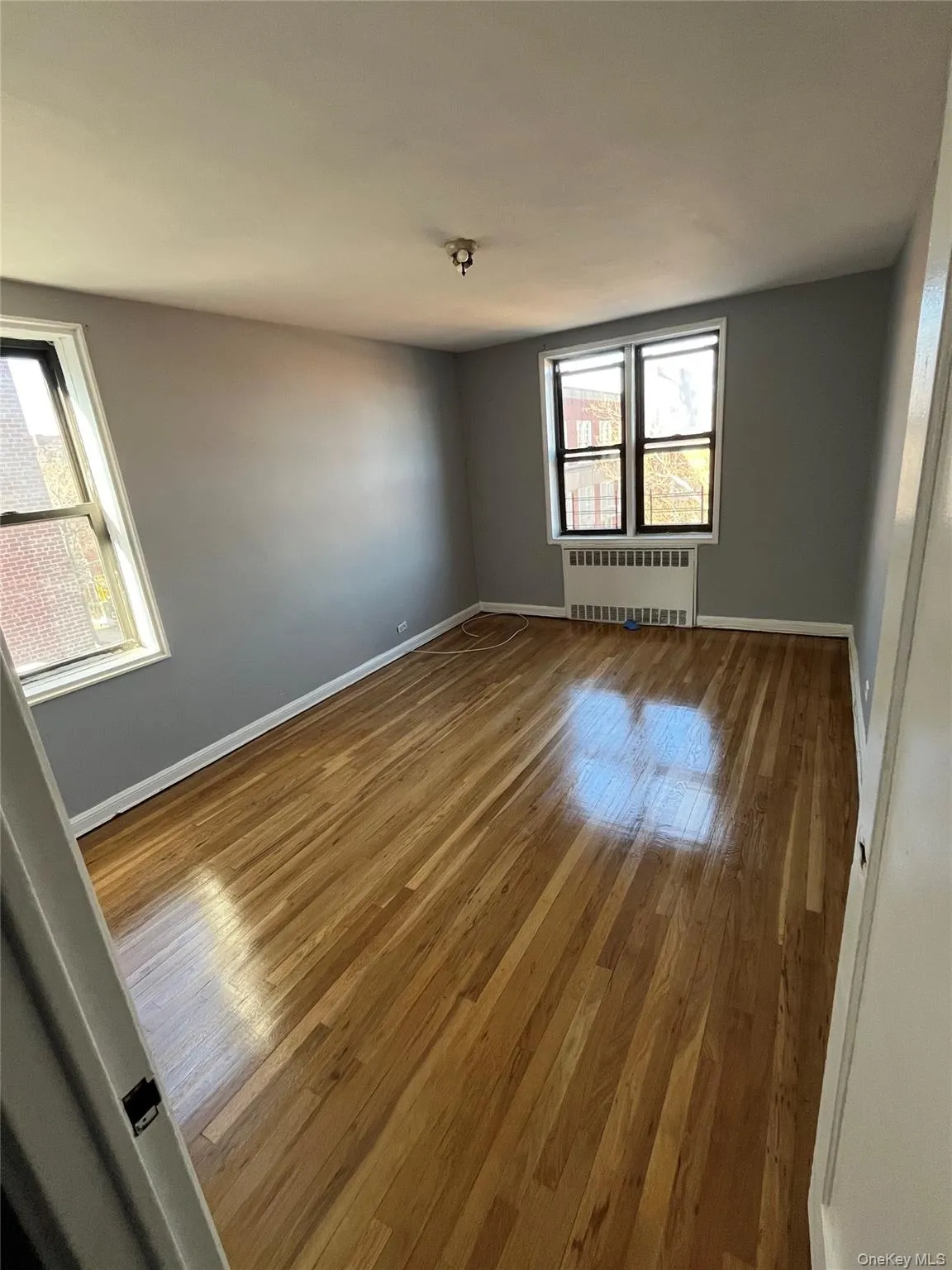 Unfurnished room featuring wood-type flooring and radiator heating unit Unfurnished room featuring wood-type flooring and radiator heating unit