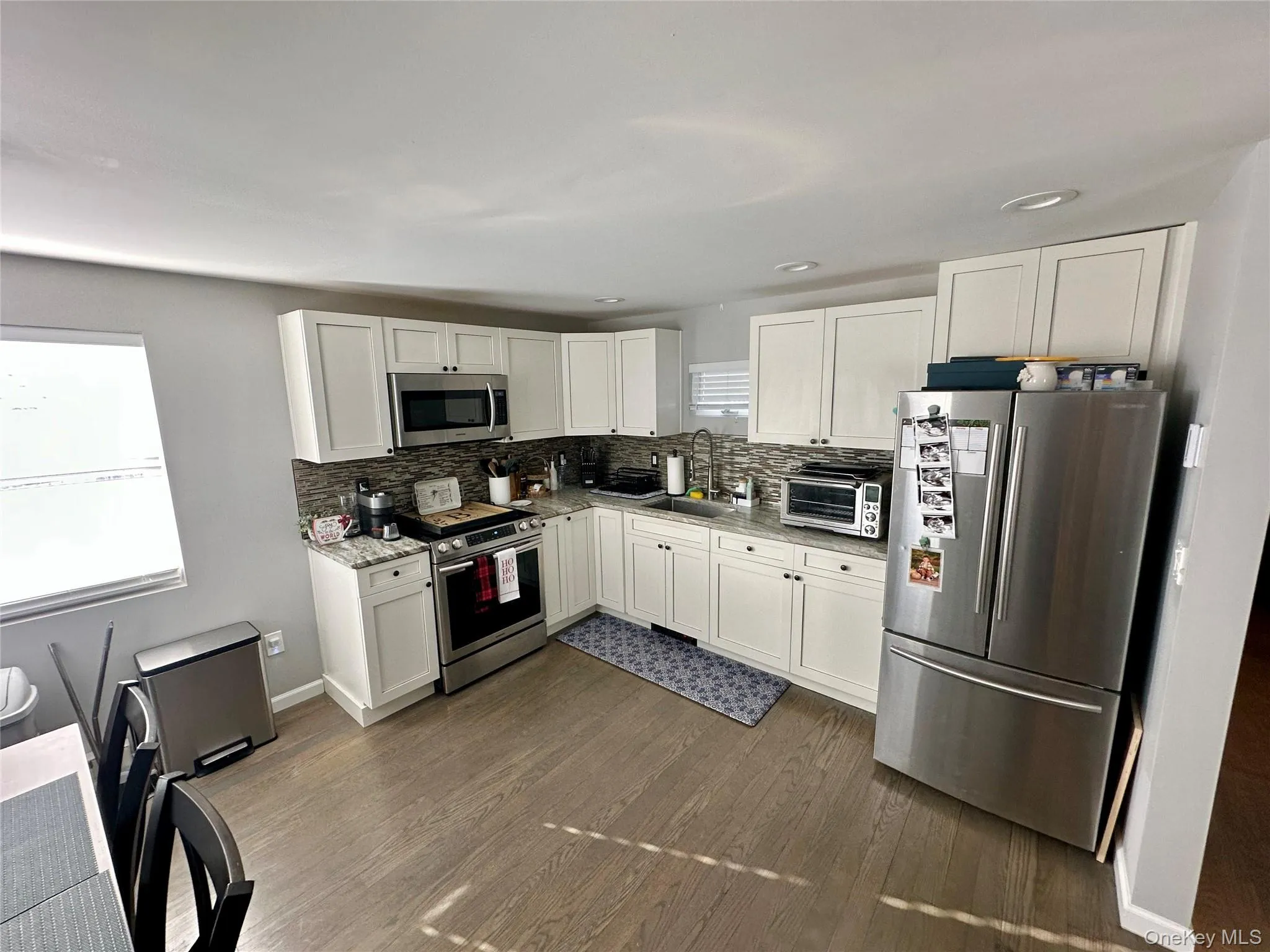 Kitchen featuring stainless steel appliances, white cabinets, dark wood finished floors, and tasteful backsplash Kitchen featuring stainless steel appliances, white cabinets, dark wood finished floors, and tasteful backsplash