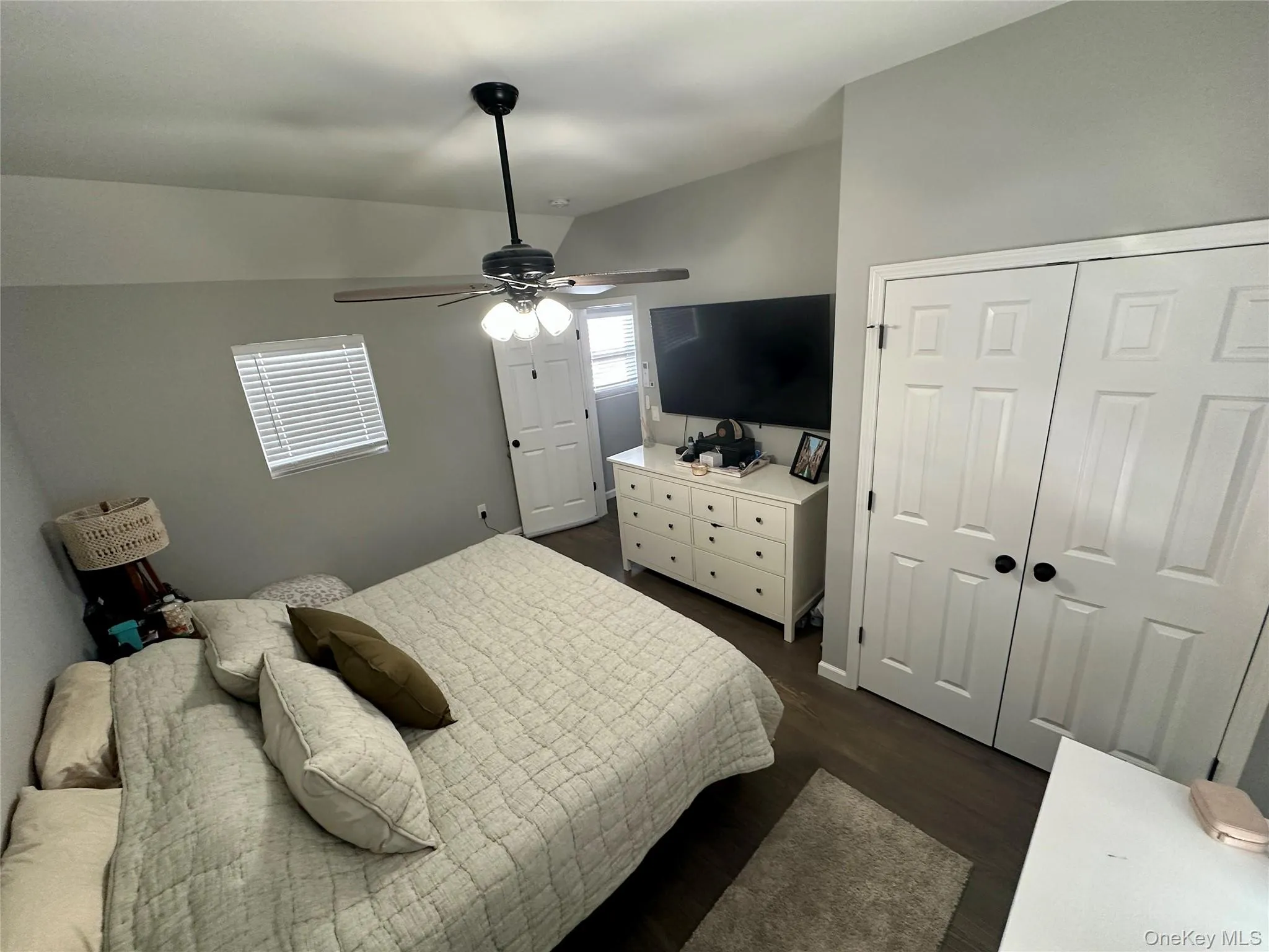 Bedroom with dark wood-style floors, lofted ceiling, and a ceiling fan Bedroom with dark wood-style floors, lofted ceiling, and a ceiling fan