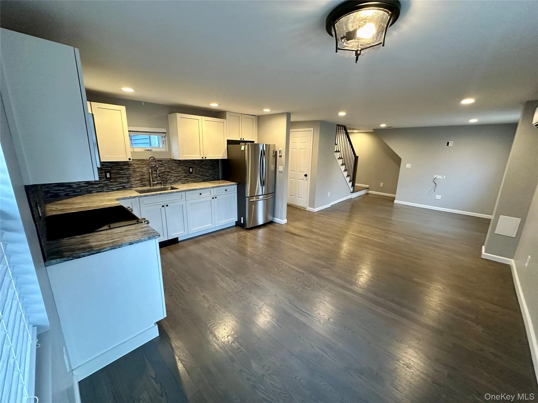 Kitchen with white cabinets, tasteful backsplash, freestanding refrigerator, dark wood-type flooring, and recessed lighting Kitchen with white cabinets, tasteful backsplash, freestanding refrigerator, dark wood-type flooring, and recessed lighting