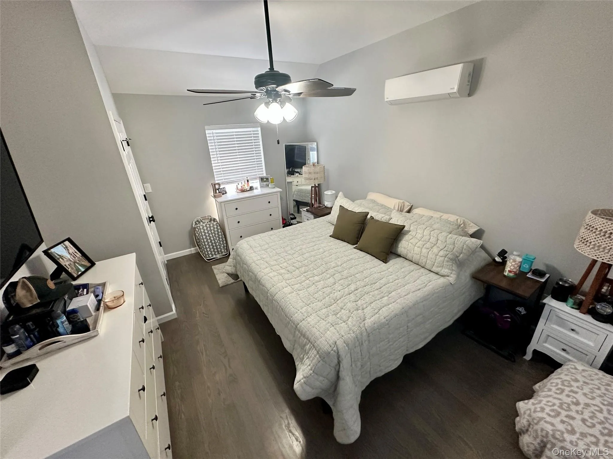 Bedroom with dark wood-style floors, a wall mounted air conditioner, and a ceiling fan Bedroom with dark wood-style floors, a wall mounted air conditioner, and a ceiling fan