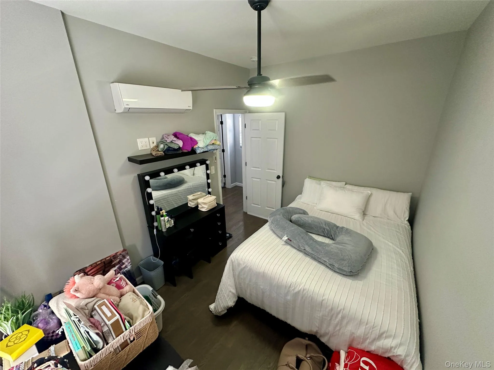 Bedroom with dark wood finished floors, a ceiling fan, and a wall unit AC Bedroom with dark wood finished floors, a ceiling fan, and a wall unit AC