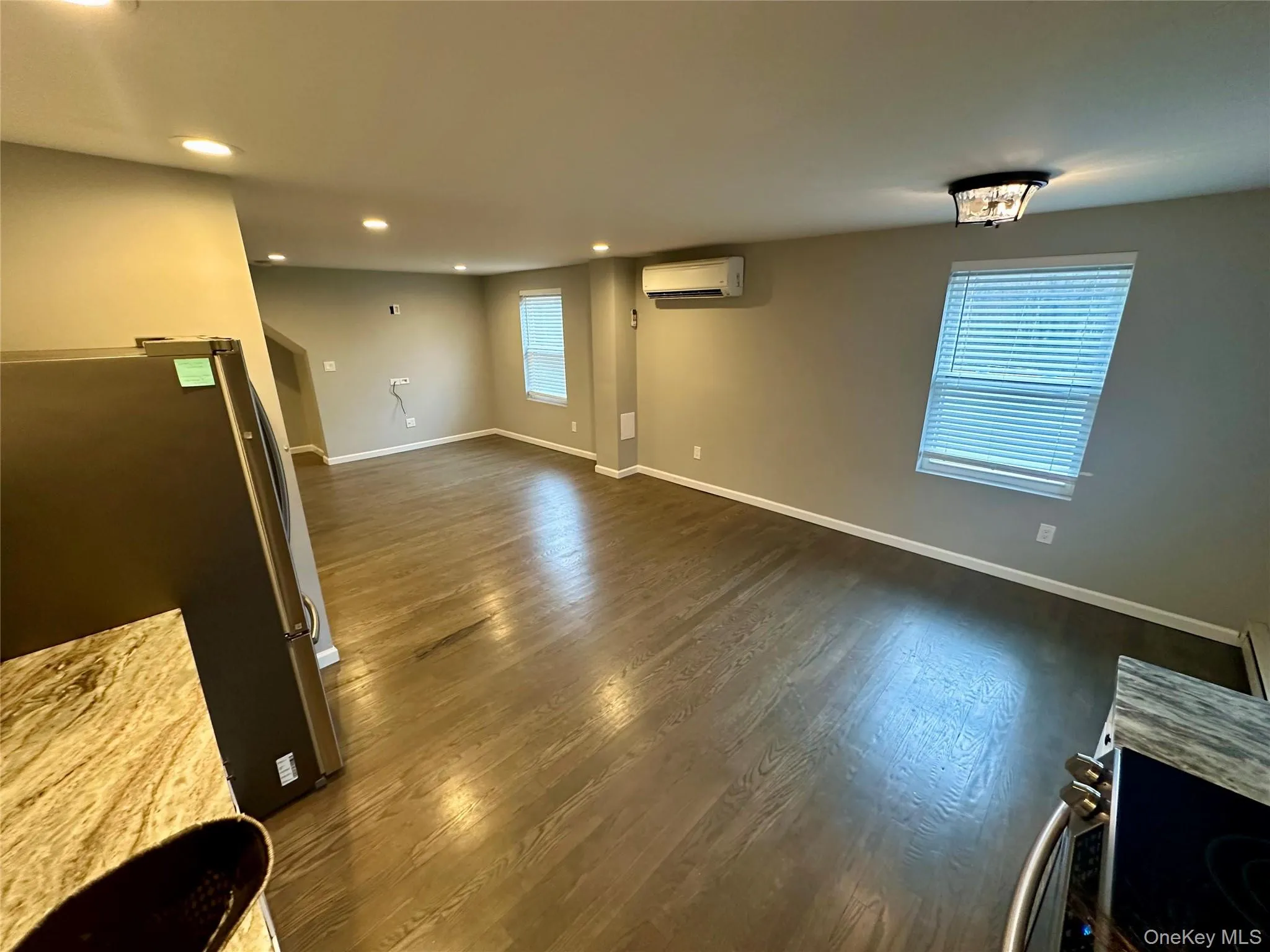 Unfurnished living room featuring recessed lighting, dark wood-type flooring, and a wall unit AC Unfurnished living room featuring recessed lighting, dark wood-type flooring, and a wall unit AC
