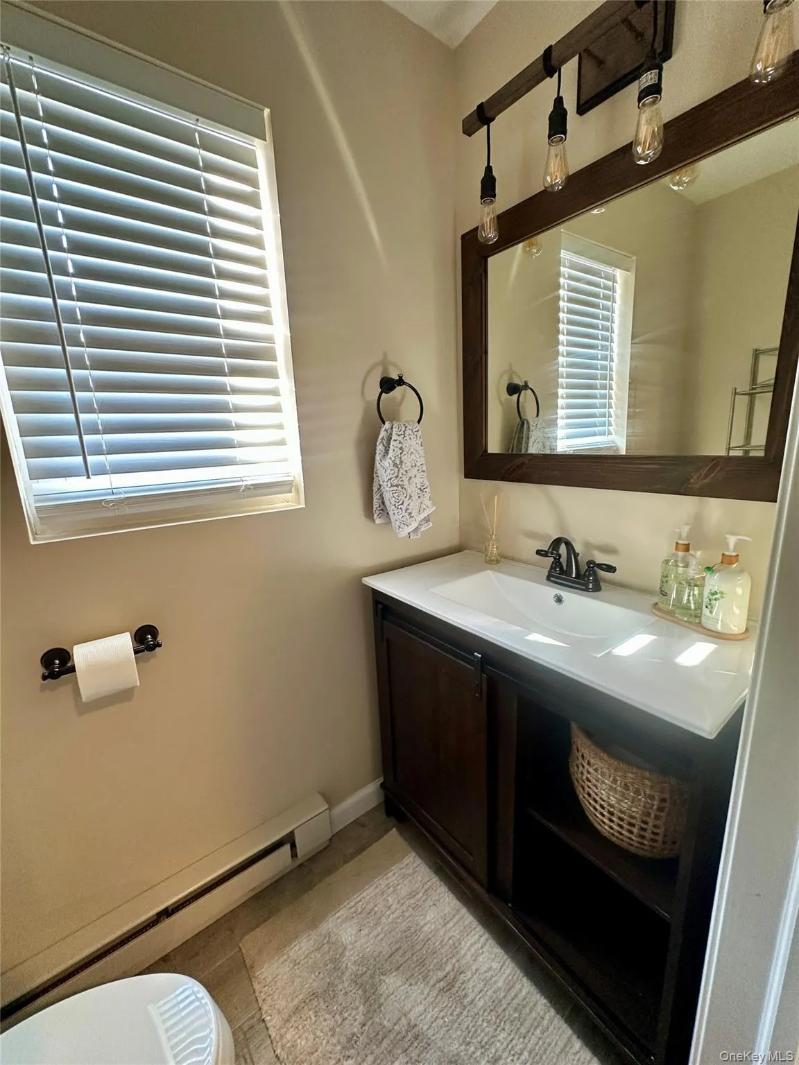 Bathroom with baseboard heating, vanity, and healthy amount of natural light Bathroom with baseboard heating, vanity, and healthy amount of natural light