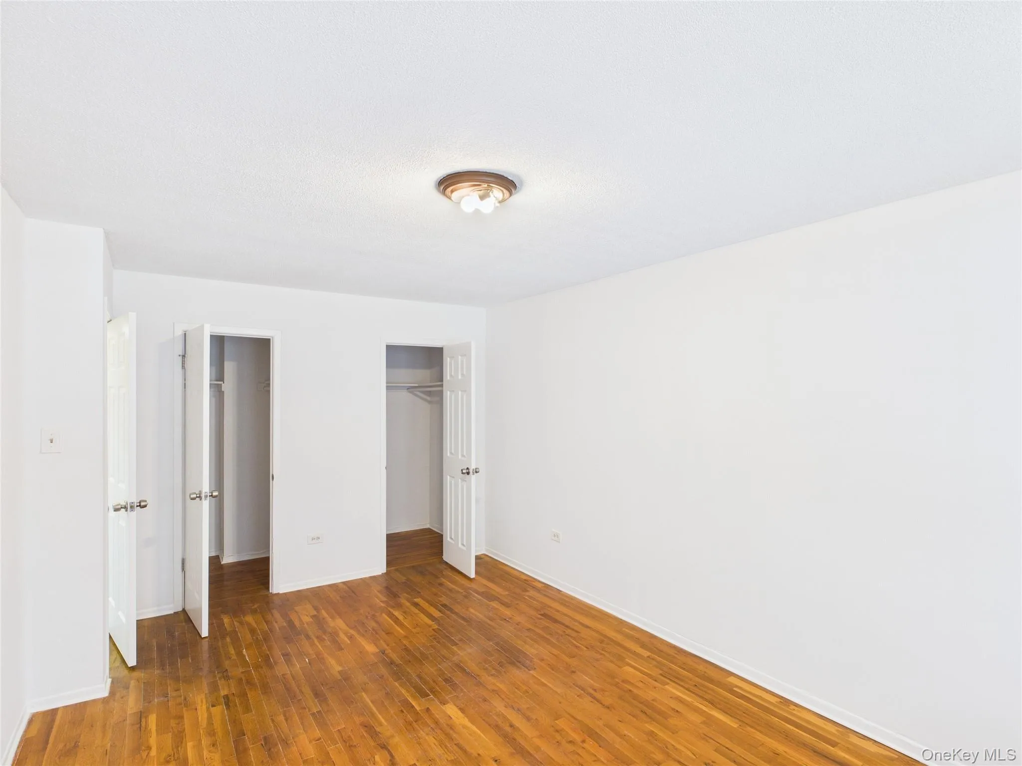 Unfurnished bedroom with wood-type flooring and a closet Unfurnished bedroom with wood-type flooring and a closet