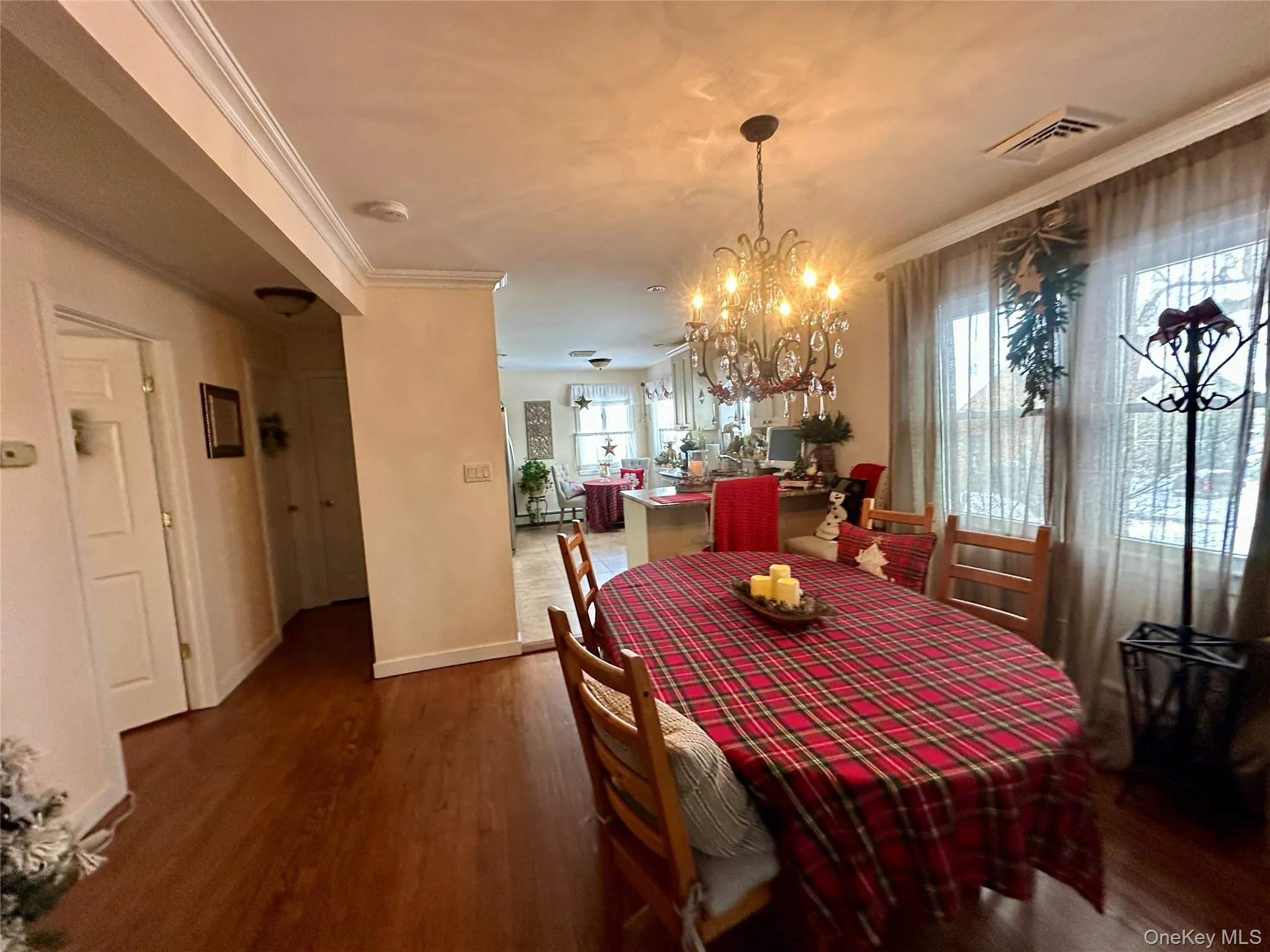 Dining area featuring crown molding, dark wood-type flooring, and a chandelier Dining area featuring crown molding, dark wood-type flooring, and a chandelier