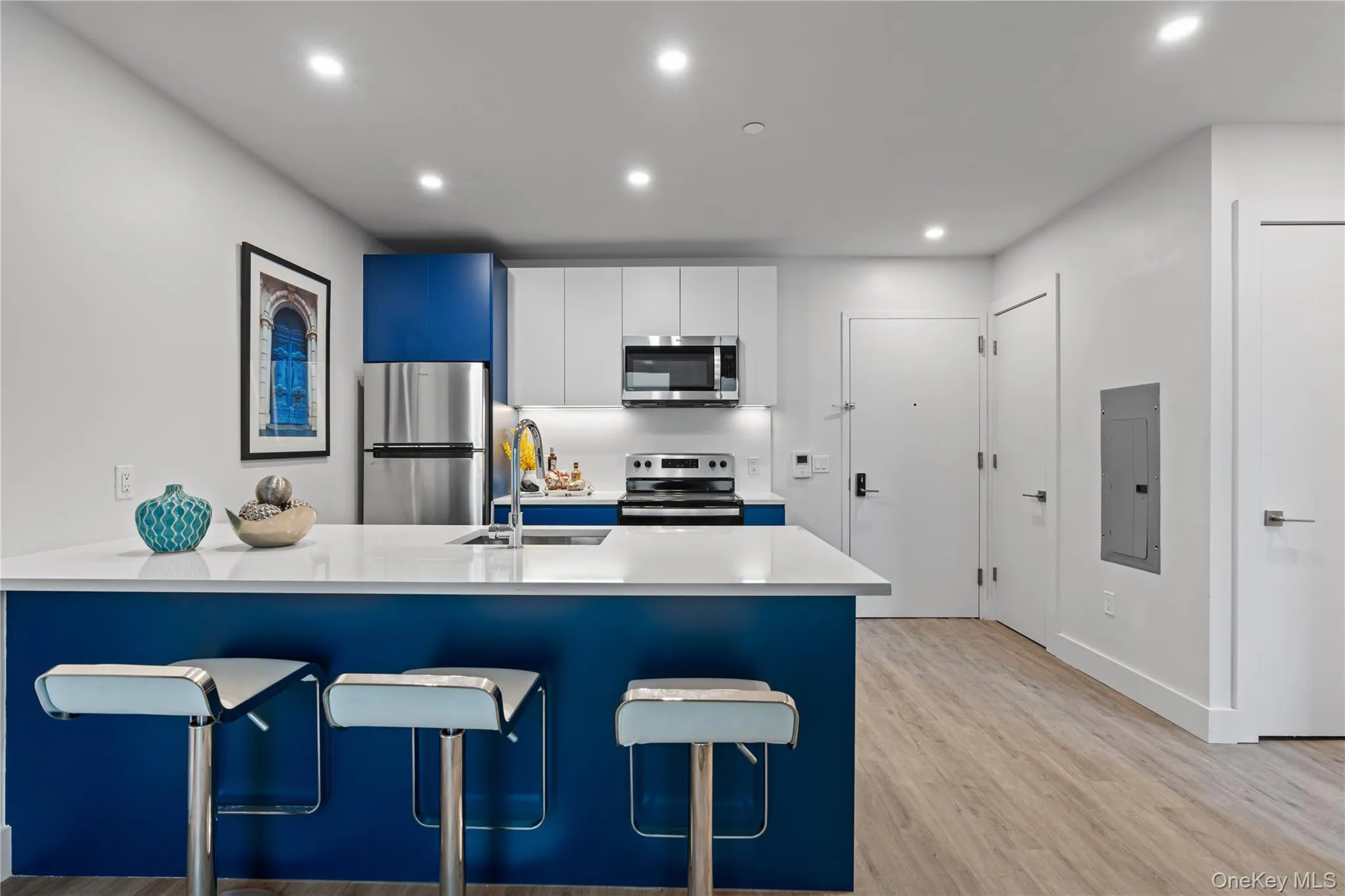 Kitchen featuring a breakfast bar, a peninsula, white cabinets, recessed lighting, and blue cabinetry Kitchen featuring a breakfast bar, a peninsula, white cabinets, recessed lighting, and blue cabinetry