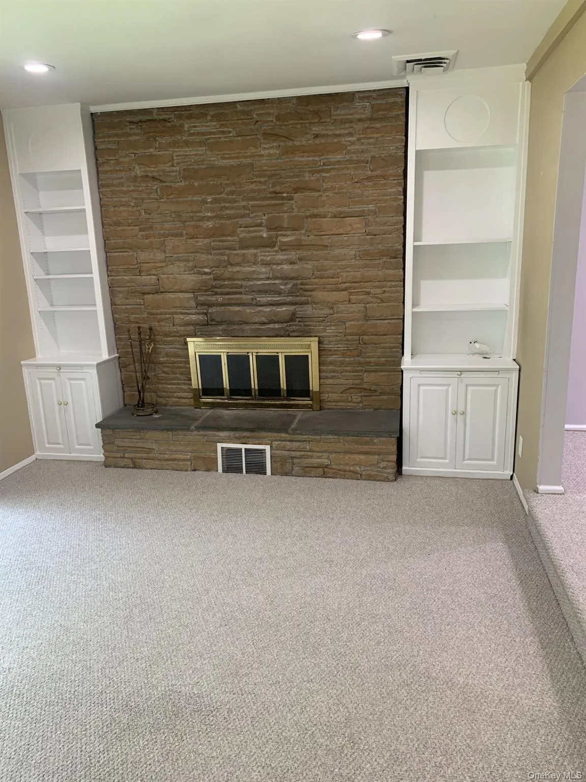 Family Room featuring built in features, a stone fireplace, carpet flooring, and recessed lighting Family Room featuring built in features, a stone fireplace, carpet flooring, and recessed lighting