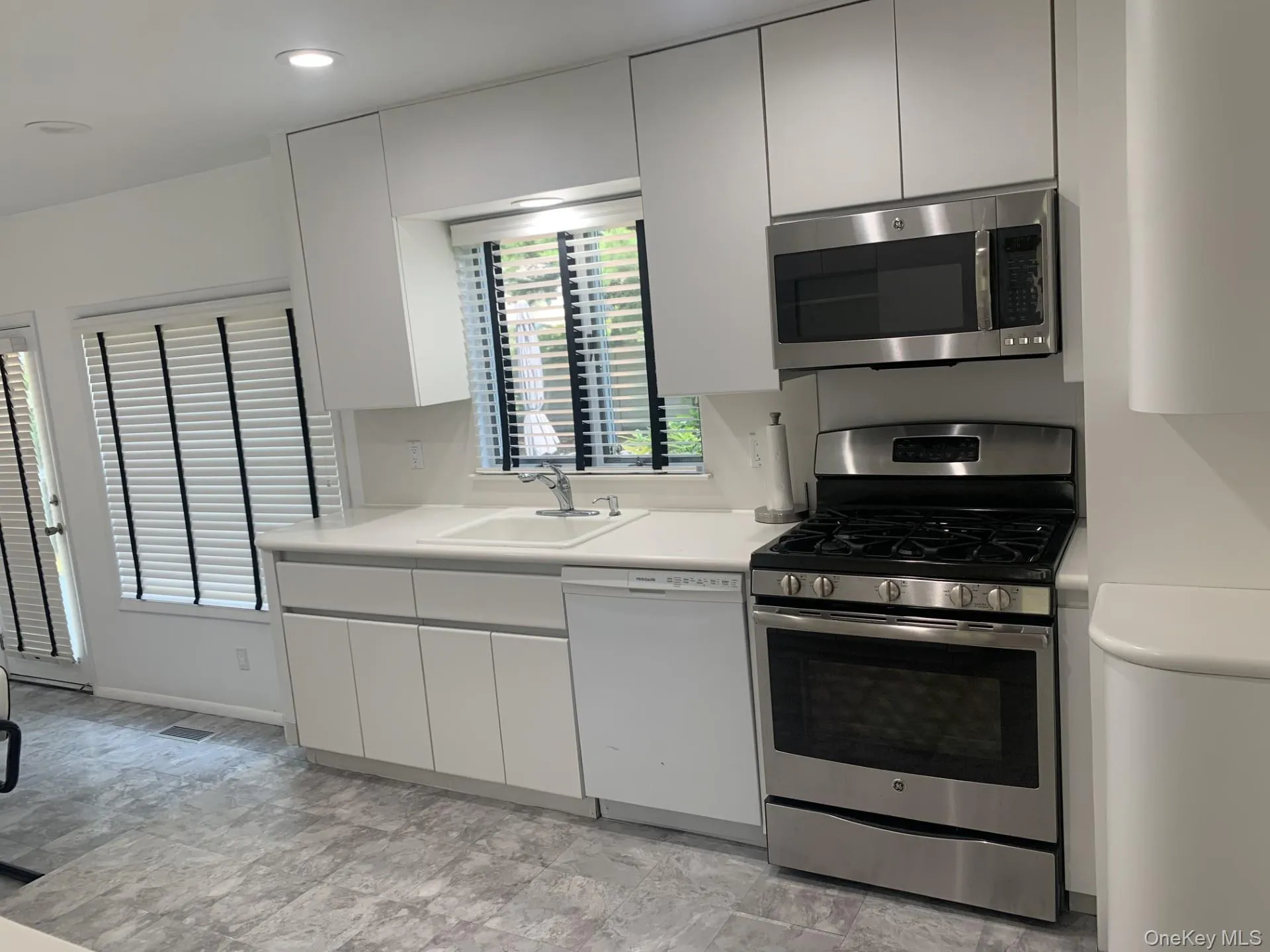 Kitchen with stainless steel appliances, light countertops, white cabinets, modern cabinets, and recessed lighting Kitchen with stainless steel appliances, light countertops, white cabinets, modern cabinets, and recessed lighting