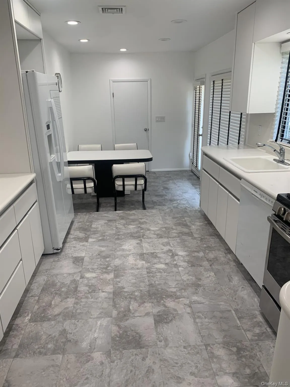 Kitchen with light countertops, white cabinetry, modern cabinets, and recessed lighting Kitchen with light countertops, white cabinetry, modern cabinets, and recessed lighting