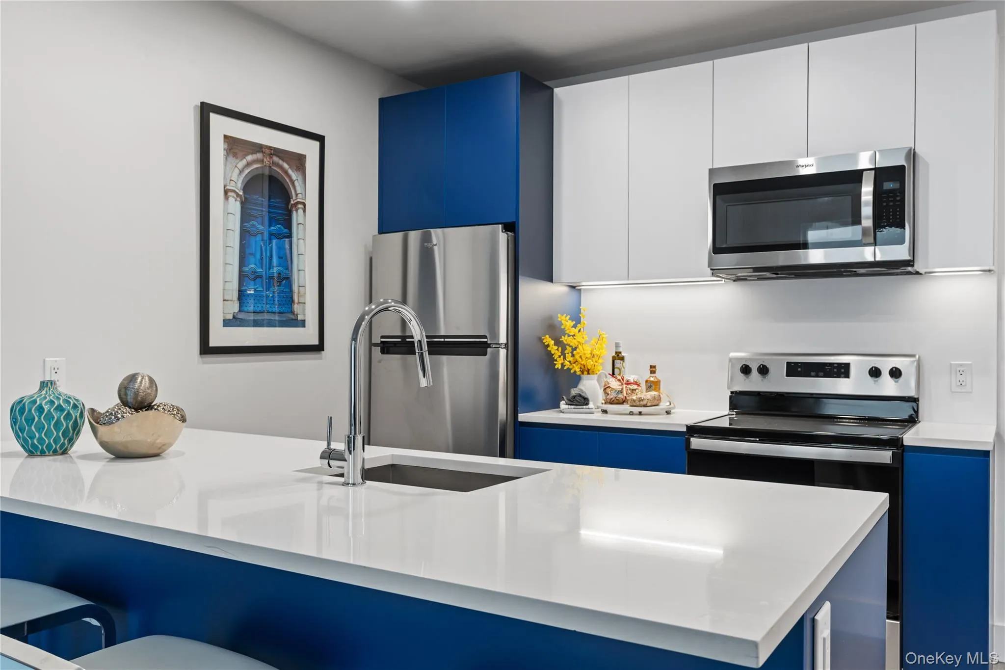 Kitchen featuring blue cabinetry, stainless steel appliances, modern cabinets, a breakfast bar area, and light stone counters Kitchen featuring blue cabinetry, stainless steel appliances, modern cabinets, a breakfast bar area, and light stone counters