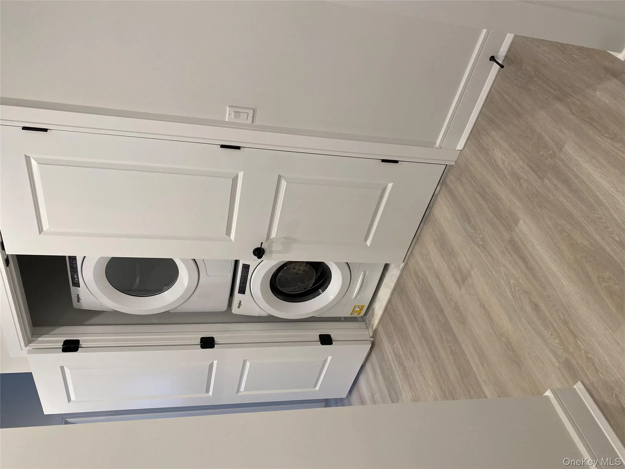 Laundry room featuring stacked washer and clothes dryer and light wood-style flooring Laundry room featuring stacked washer and clothes dryer and light wood-style flooring