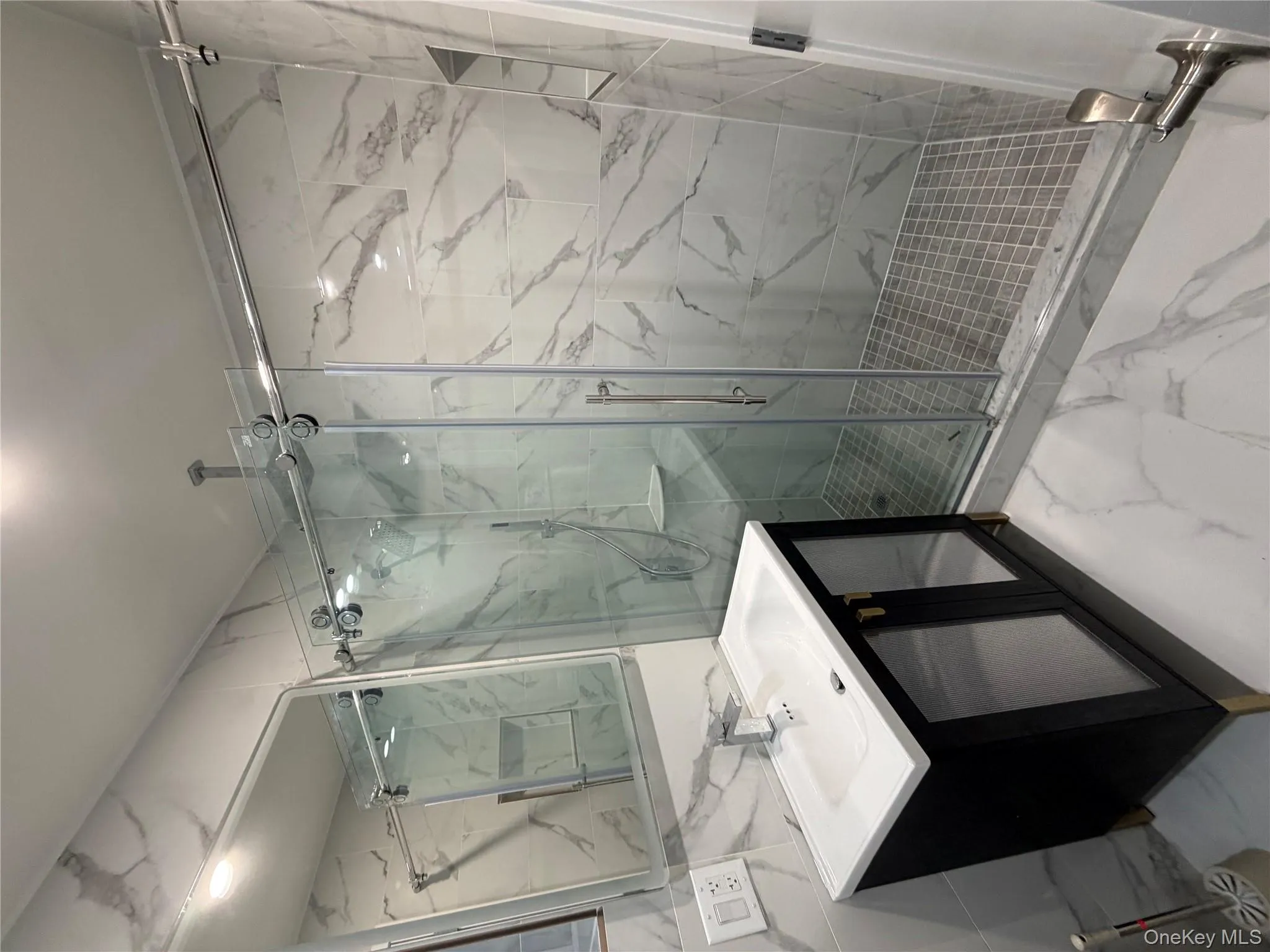Bathroom with marble tiled flooring, vanity, a marble finish shower, and tile walls Bathroom with marble tiled flooring, vanity, a marble finish shower, and tile walls