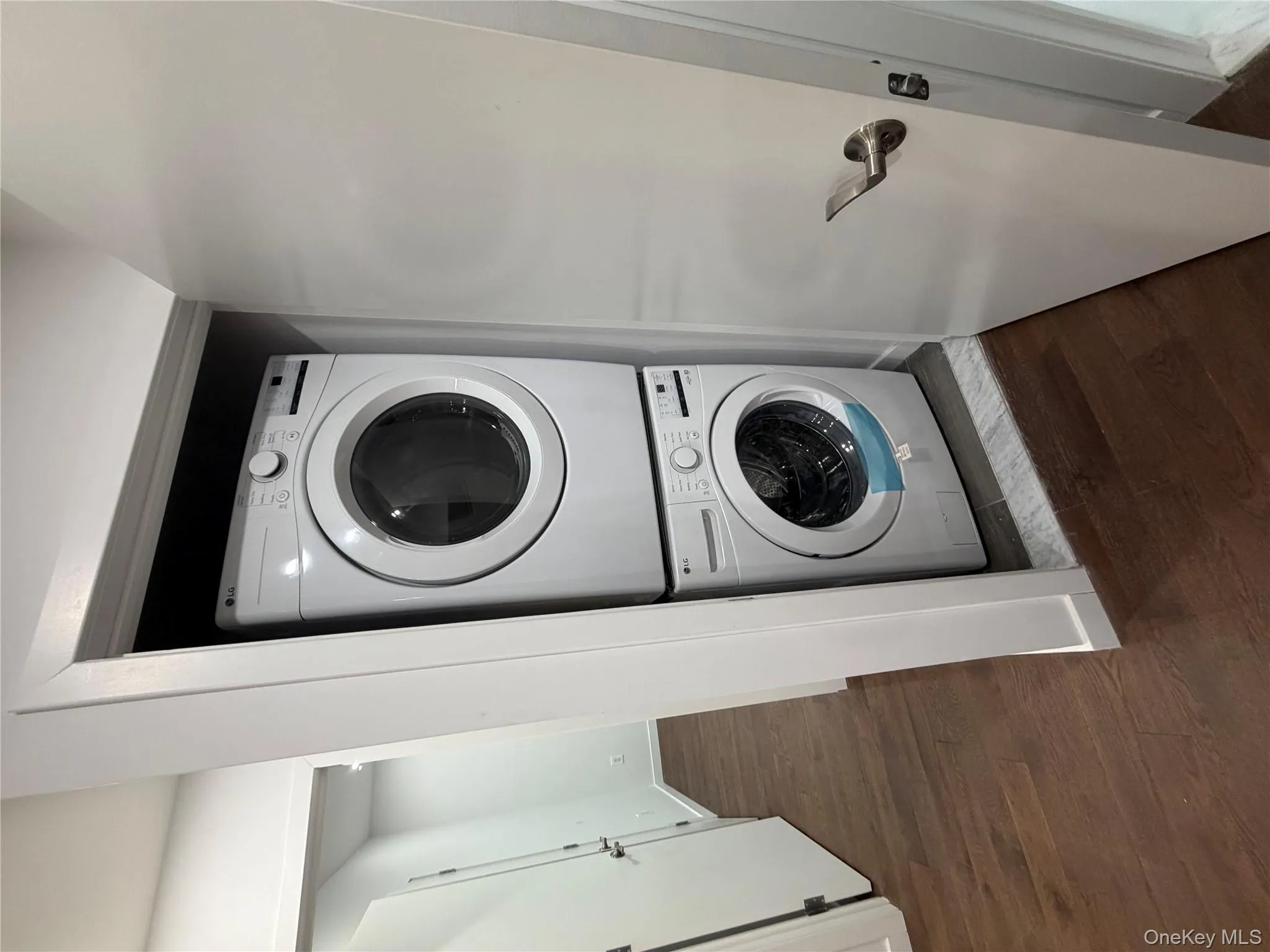 Laundry area featuring dark wood finished floors and estacked washer and dryer Laundry area featuring dark wood finished floors and estacked washer and dryer
