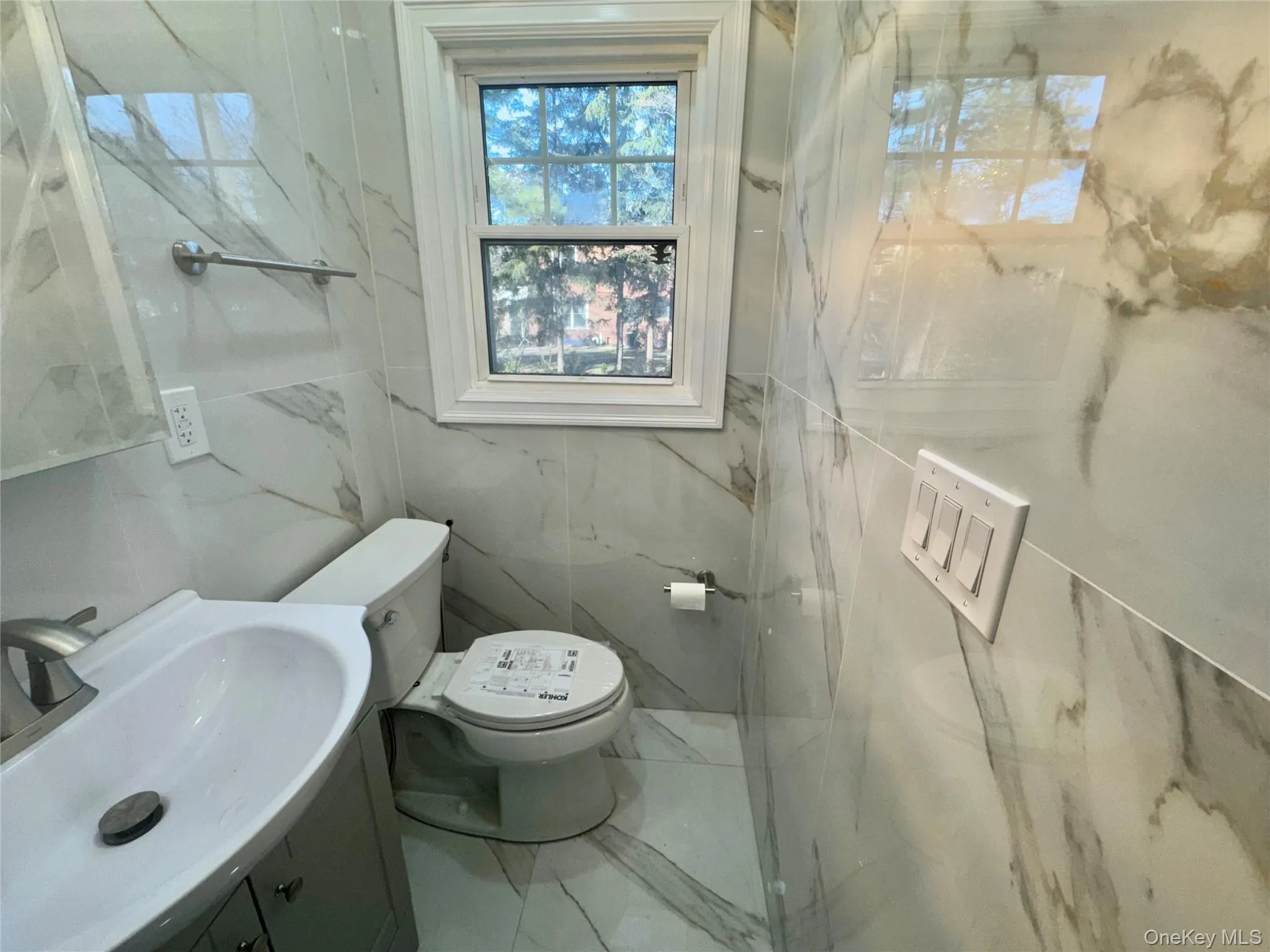 Half bath in first floor with vanity, marble tiled flooring, and a marble finish shower Half bath in first floor with vanity, marble tiled flooring, and a marble finish shower