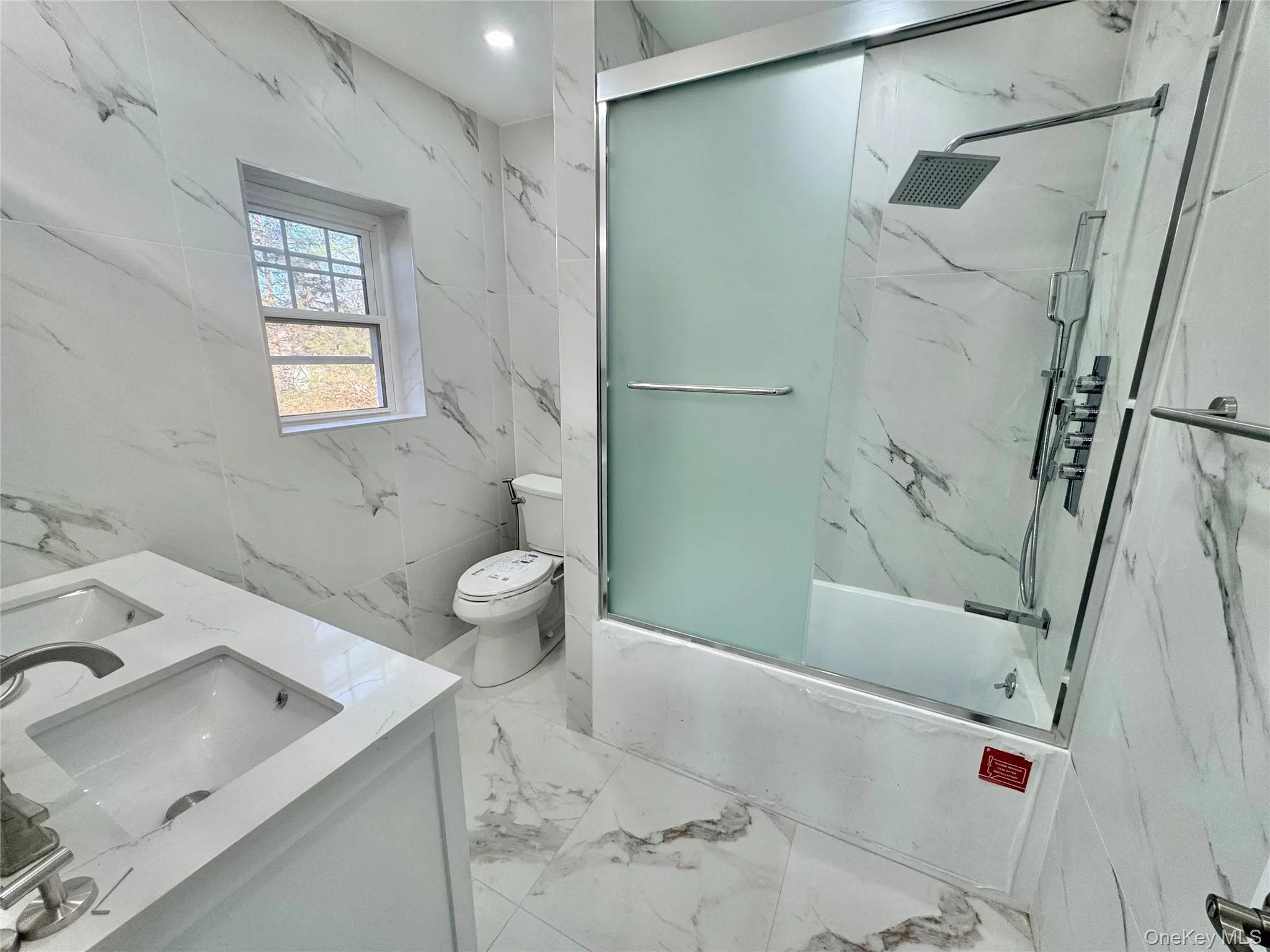 Full bathroom with double vanity, enclosed tub / shower combo, light marble finish floors, stone wall, and tile walls, window and fan Full bathroom with double vanity, enclosed tub / shower combo, light marble finish floors, stone wall, and tile walls, window and fan