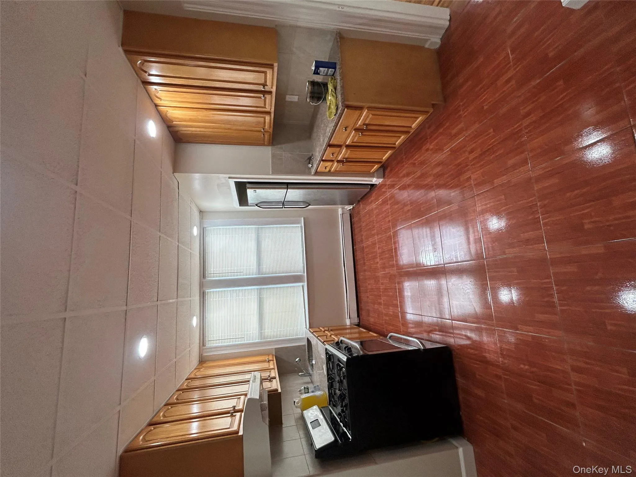 Kitchen with range, a paneled ceiling, decorative backsplash, light stone counters, and brown cabinets Kitchen with range, a paneled ceiling, decorative backsplash, light stone counters, and brown cabinets