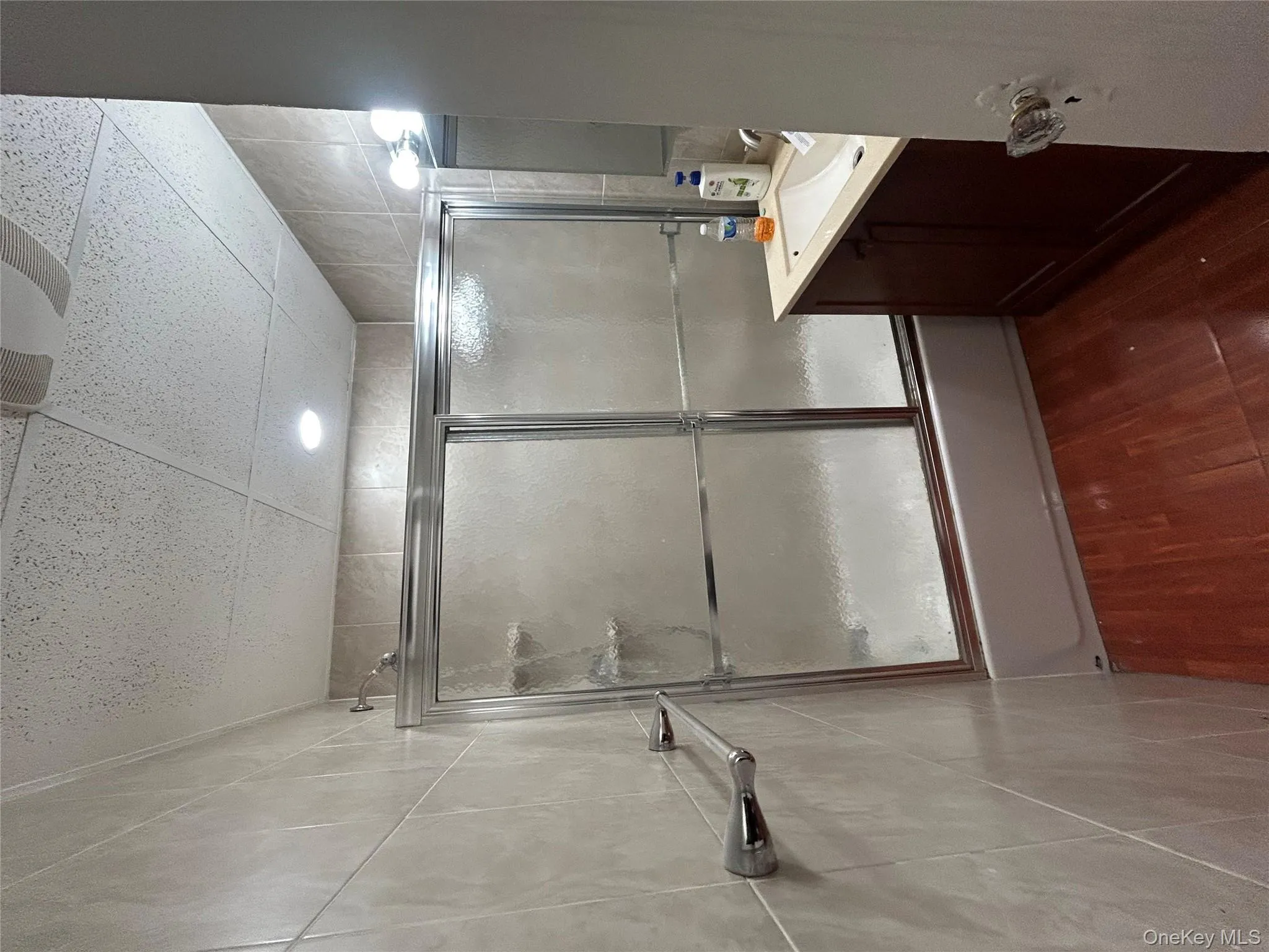 Bathroom featuring vanity, enclosed tub / shower combo, dark wood-style flooring, and a paneled ceiling Bathroom featuring vanity, enclosed tub / shower combo, dark wood-style flooring, and a paneled ceiling