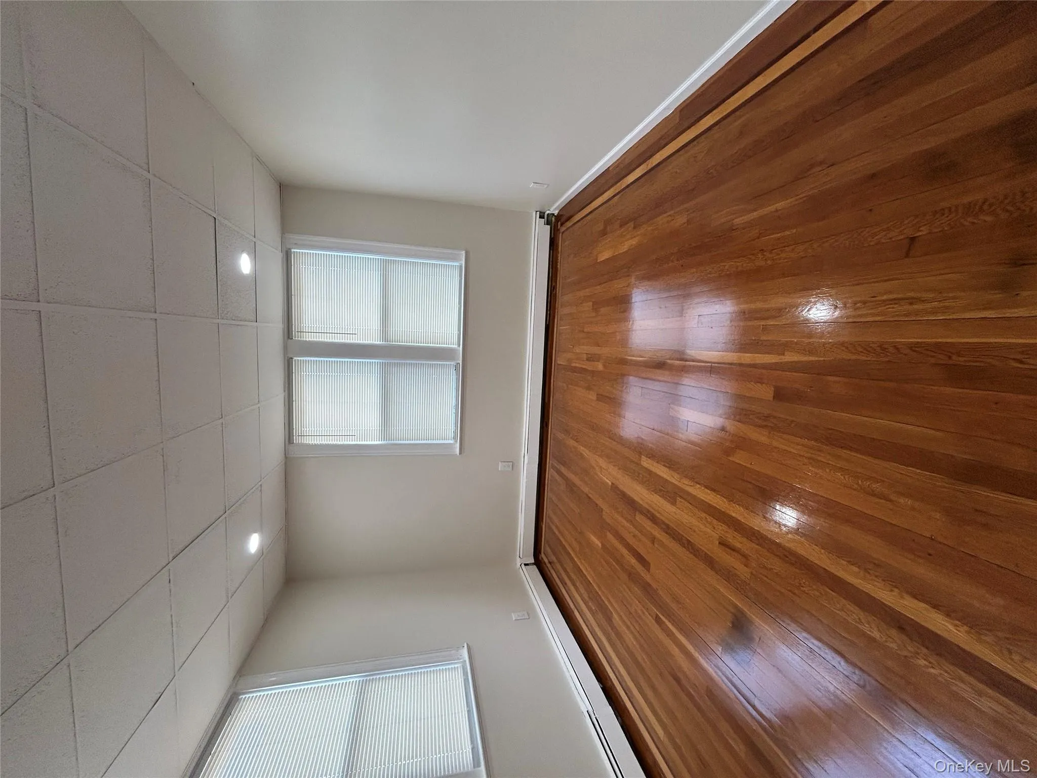 Empty room with a drop ceiling, a baseboard heating unit, hardwood / wood-style flooring, and recessed lighting Empty room with a drop ceiling, a baseboard heating unit, hardwood / wood-style flooring, and recessed lighting