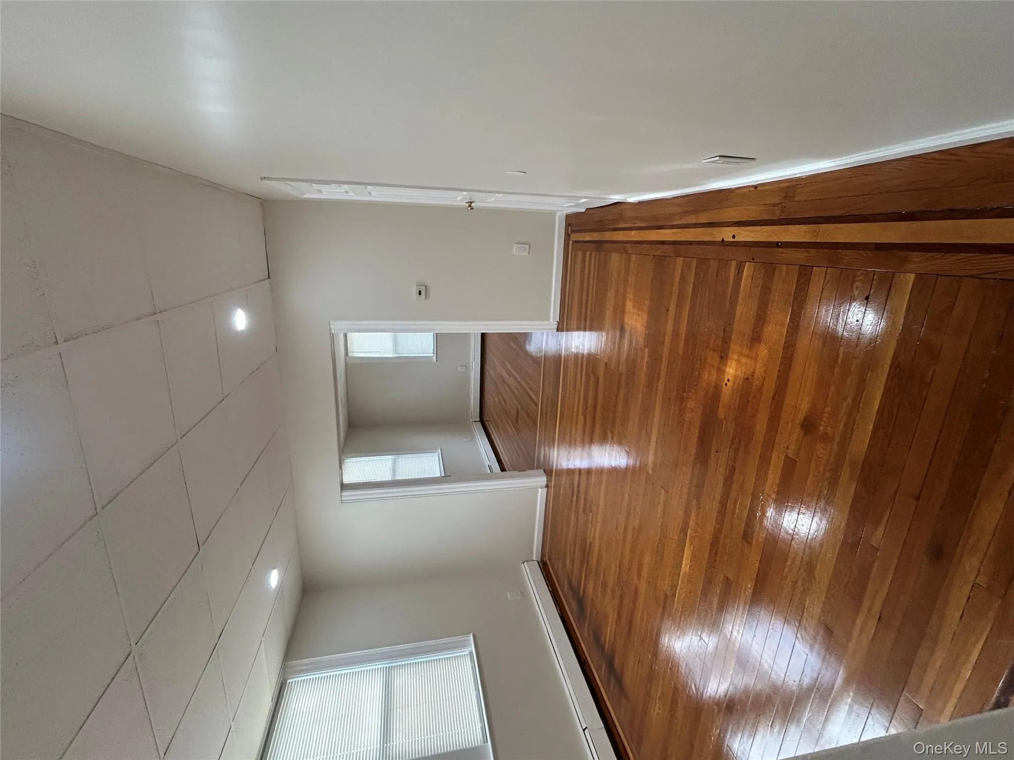 Empty room featuring baseboard heating, wood-type flooring, and a drop ceiling Empty room featuring baseboard heating, wood-type flooring, and a drop ceiling