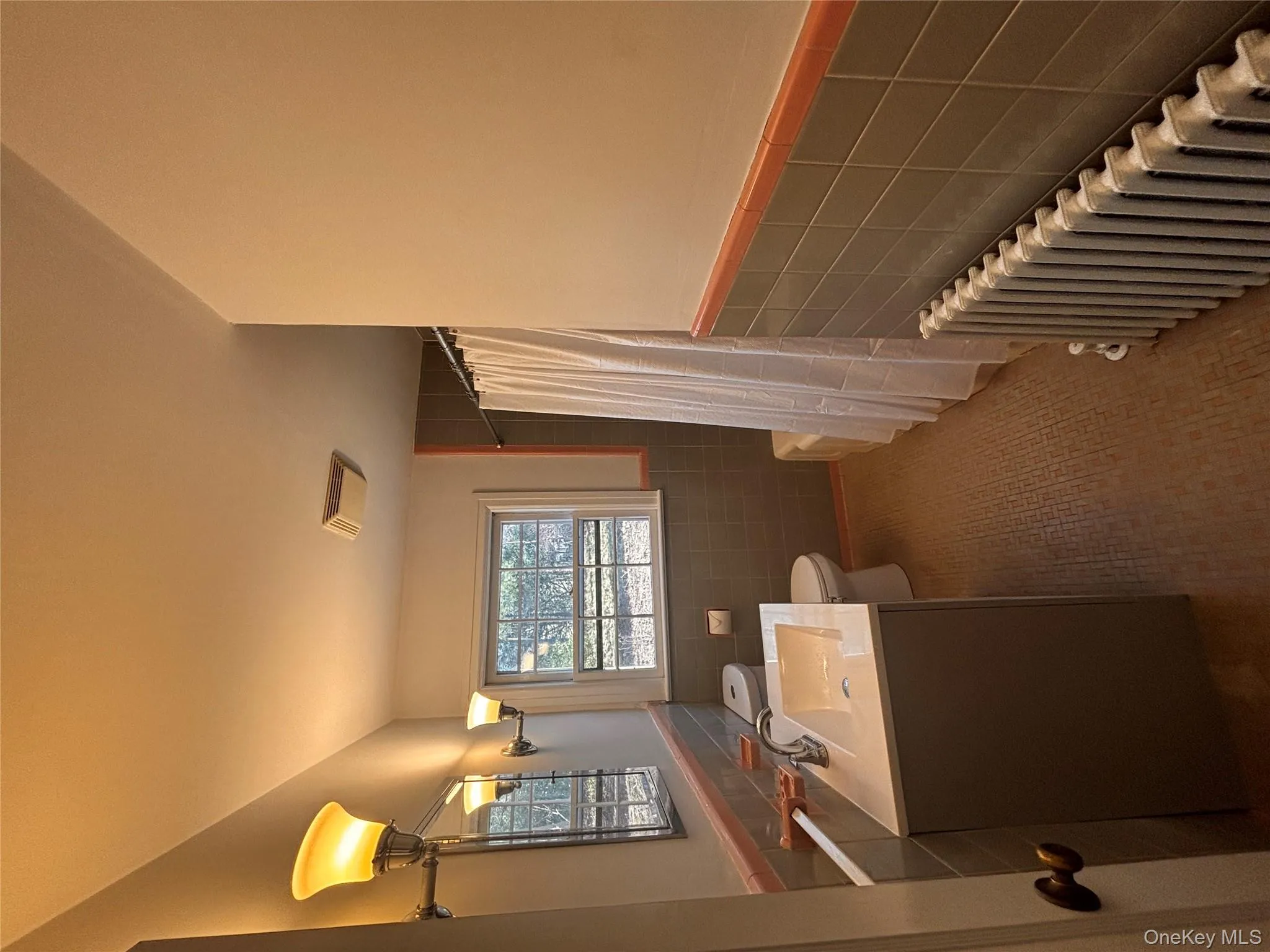 Full bath featuring tile walls, radiator, wainscoting, and vanity Full bath featuring tile walls, radiator, wainscoting, and vanity