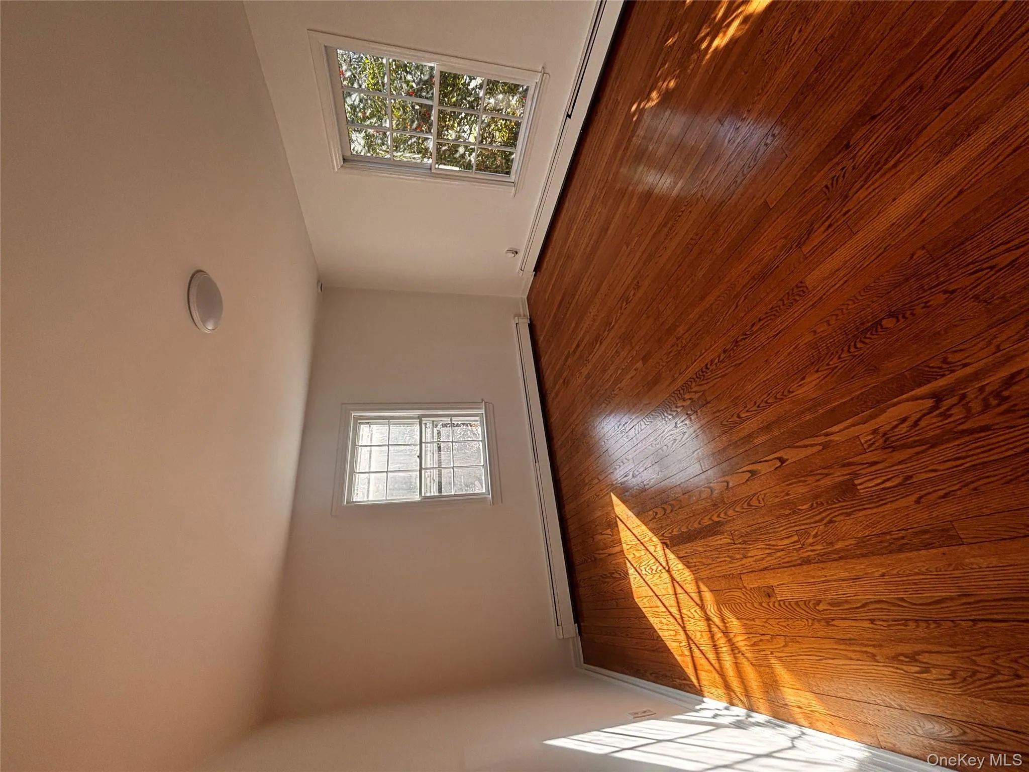 Unfurnished room featuring a baseboard heating unit, plenty of natural light, and wood-type flooring Unfurnished room featuring a baseboard heating unit, plenty of natural light, and wood-type flooring