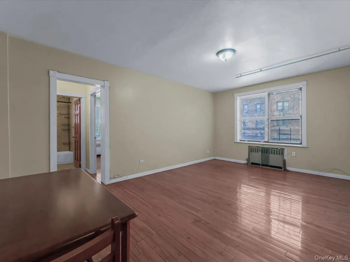 Unfurnished room featuring radiator and hardwood / wood-style floors Unfurnished room featuring radiator and hardwood / wood-style floors