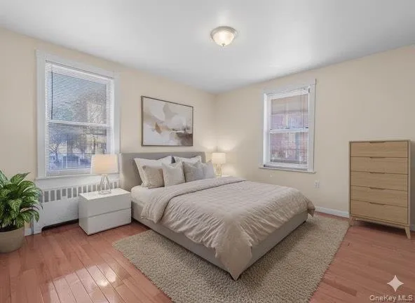 Bedroom with radiator heating unit and light wood finished floors Bedroom with radiator heating unit and light wood finished floors