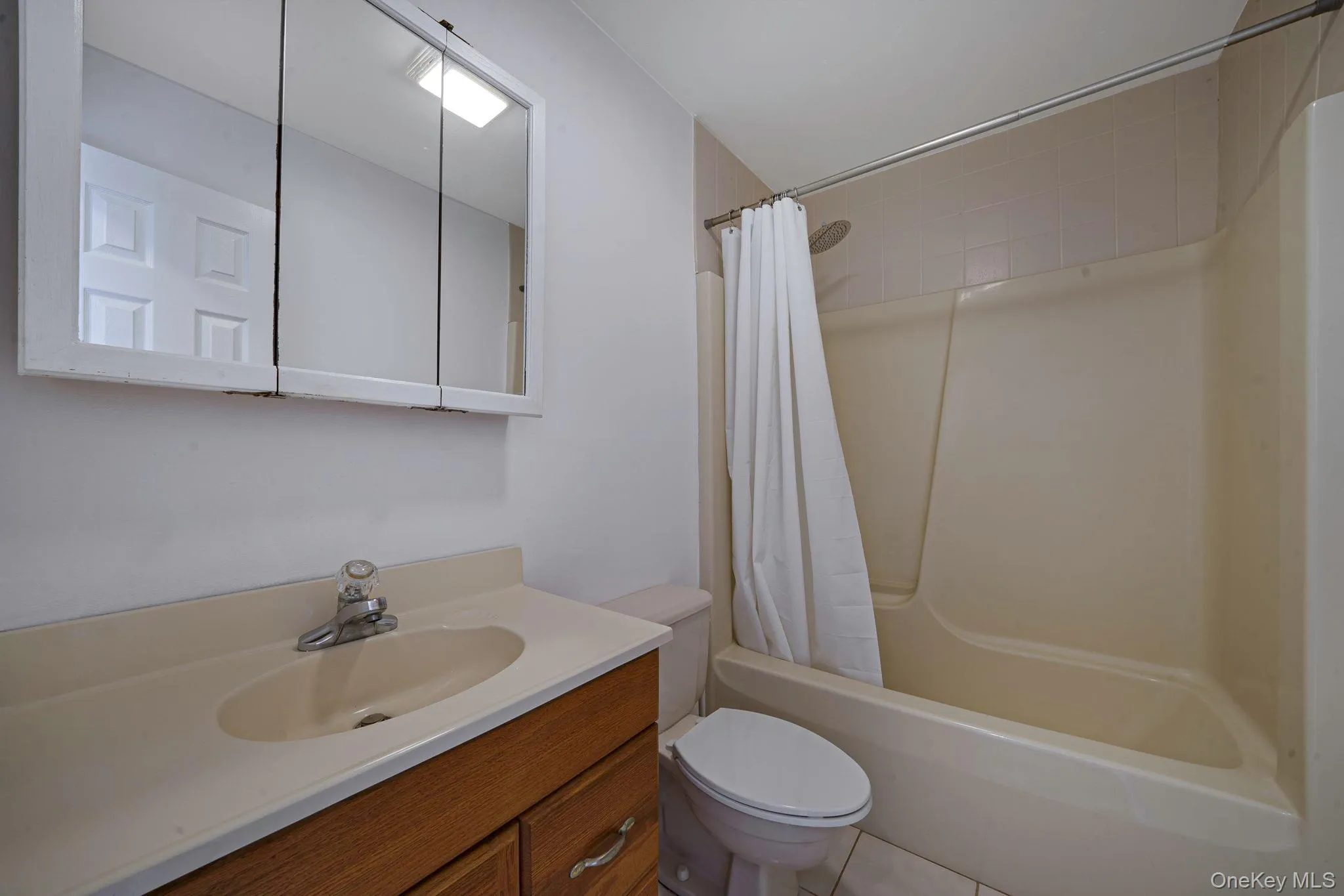 Full bath featuring vanity, shower / tub combo, and tile patterned flooring Full bath featuring vanity, shower / tub combo, and tile patterned flooring