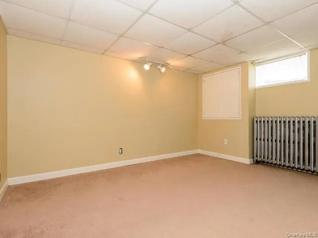 Empty room with radiator, a drop ceiling, and light colored carpet Empty room with radiator, a drop ceiling, and light colored carpet
