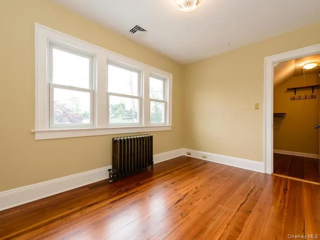 Spare room featuring radiator and dark wood finished floors Spare room featuring radiator and dark wood finished floors