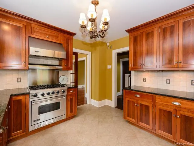 Kitchen with decorative backsplash, range hood, premium stove, and dark stone counters Kitchen with decorative backsplash, range hood, premium stove, and dark stone counters