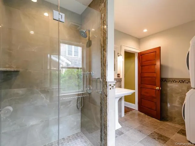 Full bathroom featuring stacked washer and clothes dryer, a stall shower, and recessed lighting Full bathroom featuring stacked washer and clothes dryer, a stall shower, and recessed lighting