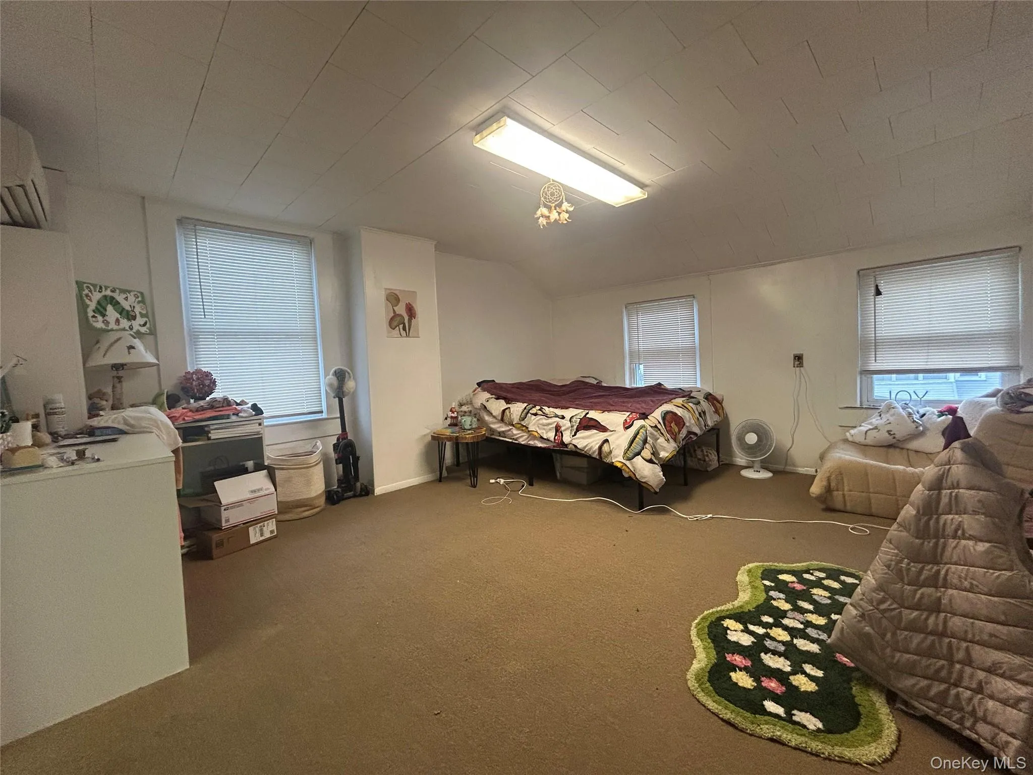 Bedroom featuring carpet, a wall unit AC, and lofted ceiling Bedroom featuring carpet, a wall unit AC, and lofted ceiling