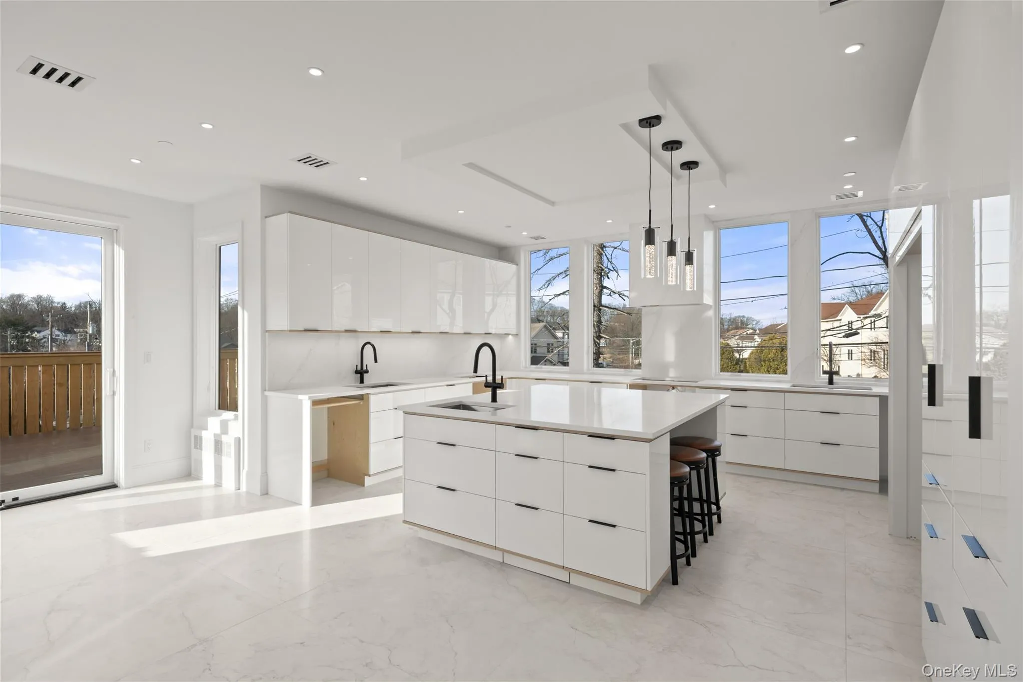 Kitchen with white cabinets, modern cabinets, hanging light fixtures, an island with sink, and light marble finish flooring Kitchen with white cabinets, modern cabinets, hanging light fixtures, an island with sink, and light marble finish flooring