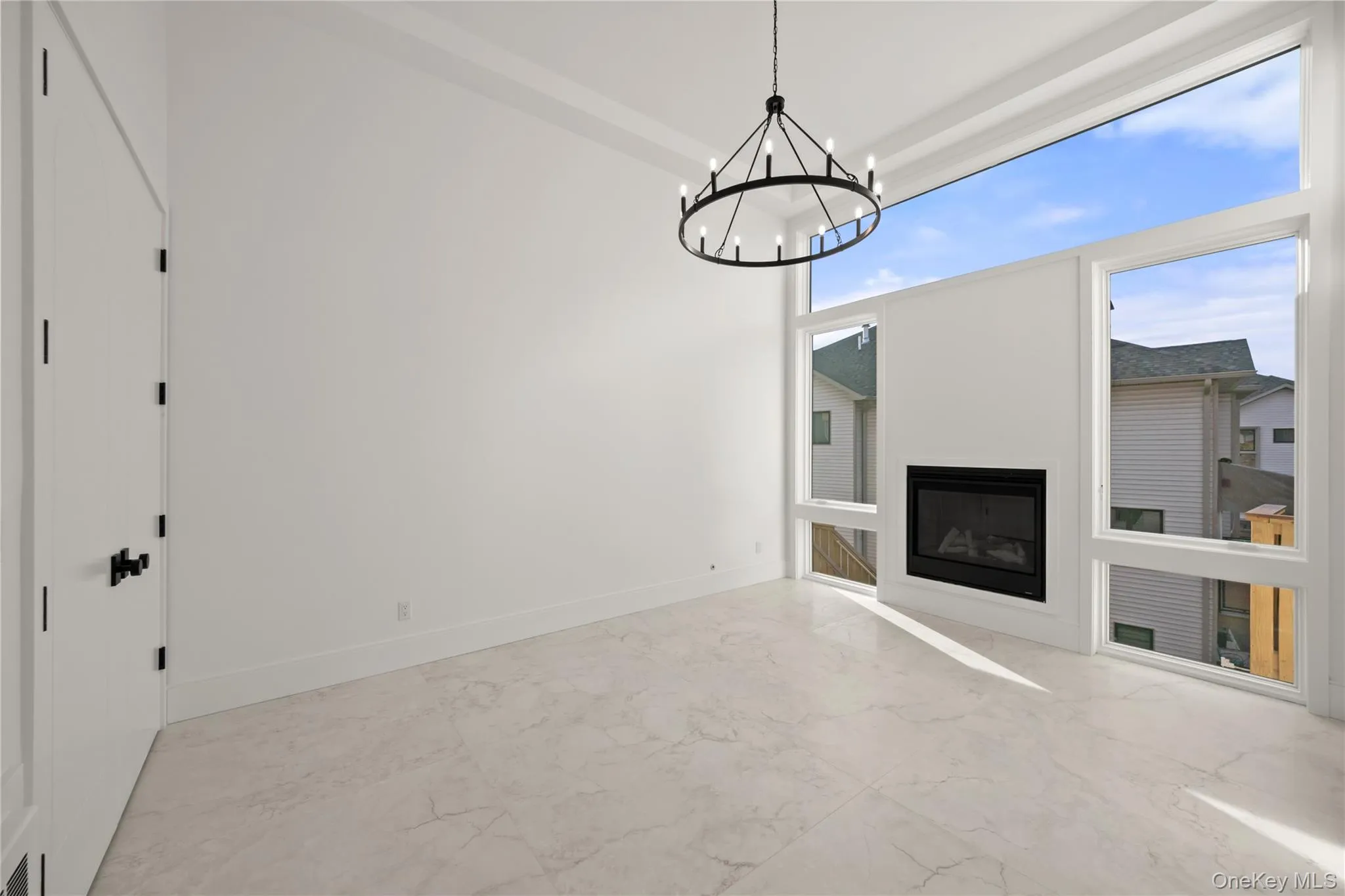 Family room featuring marble finish flooring, a glass covered fireplace, and a chandelier Family room featuring marble finish flooring, a glass covered fireplace, and a chandelier