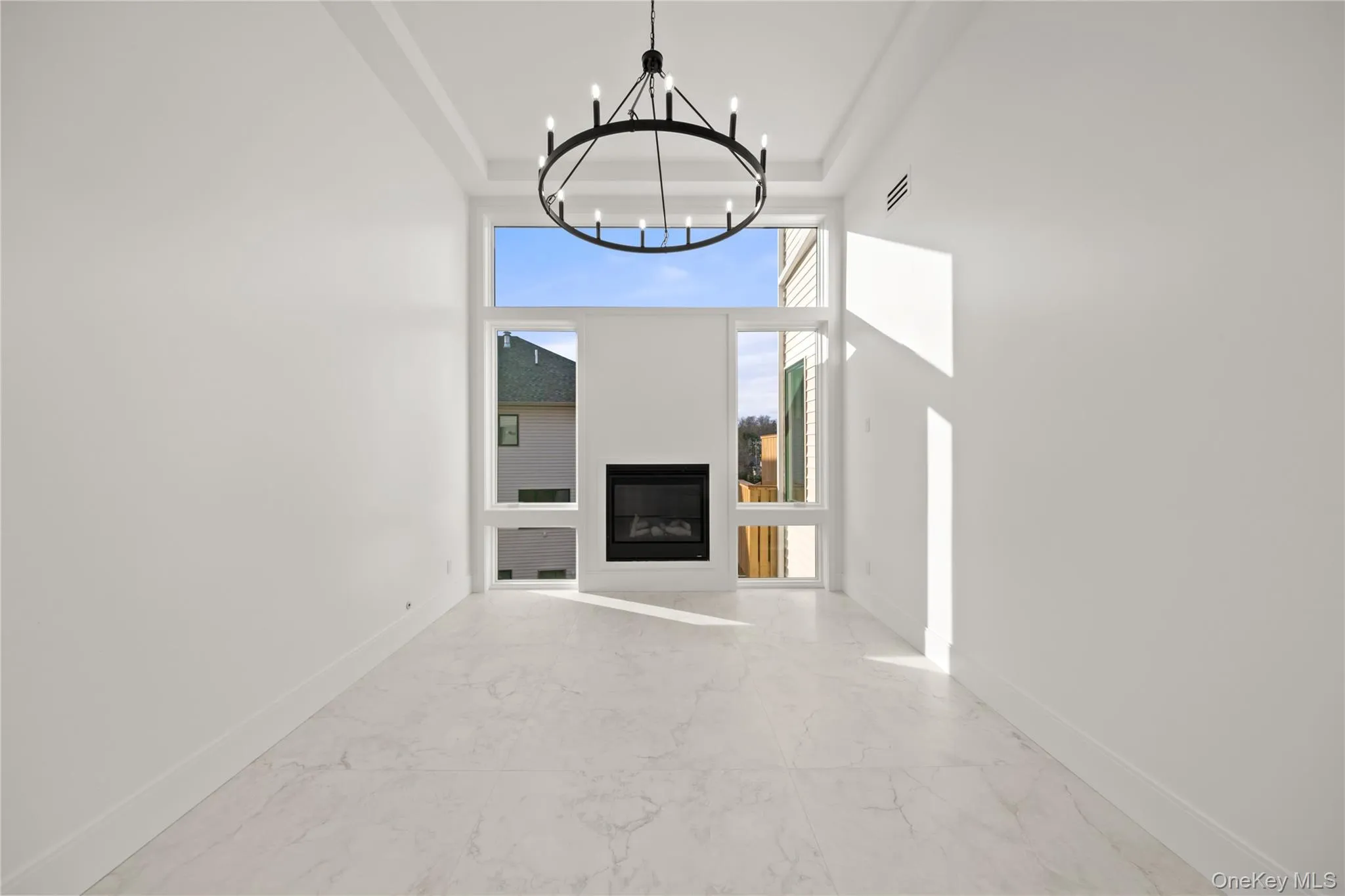 Family room featuring marble finish flooring, a glass covered fireplace, and a chandelier Family room featuring marble finish flooring, a glass covered fireplace, and a chandelier