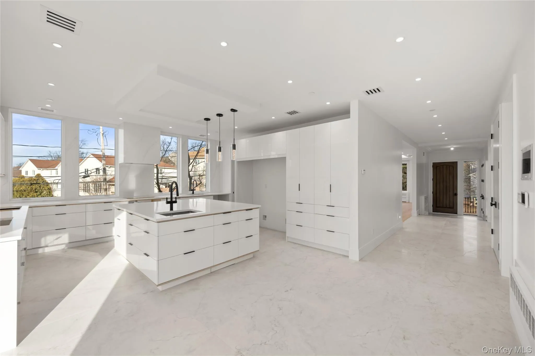 Kitchen featuring modern cabinets, hanging light fixtures, white cabinetry, a kitchen island, and light stone countertops Kitchen featuring modern cabinets, hanging light fixtures, white cabinetry, a kitchen island, and light stone countertops