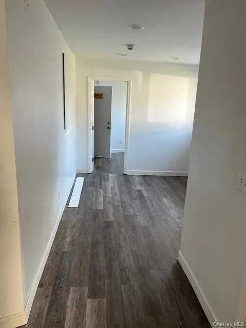 Corridor with baseboards and dark wood finished floors Corridor with baseboards and dark wood finished floors