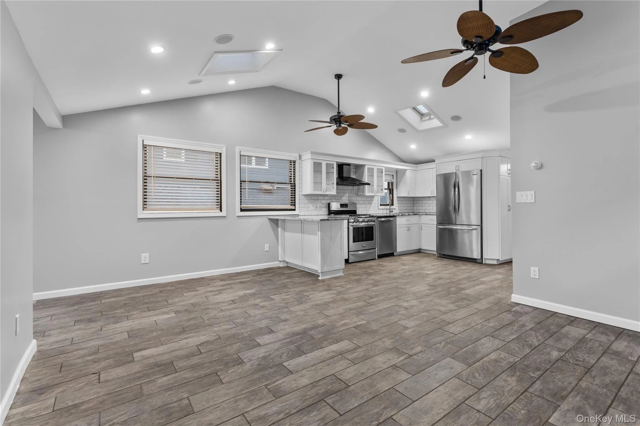 Kitchen with open floor plan, a ceiling fan, stainless steel appliances, white cabinetry, and glass insert cabinets Kitchen with open floor plan, a ceiling fan, stainless steel appliances, white cabinetry, and glass insert cabinets
