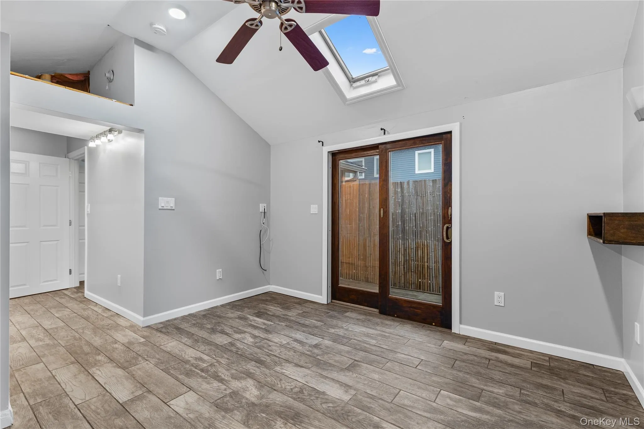 Foyer featuring ceiling fan, a skylight, light wood-type flooring, and vaulted ceiling Foyer featuring ceiling fan, a skylight, light wood-type flooring, and vaulted ceiling