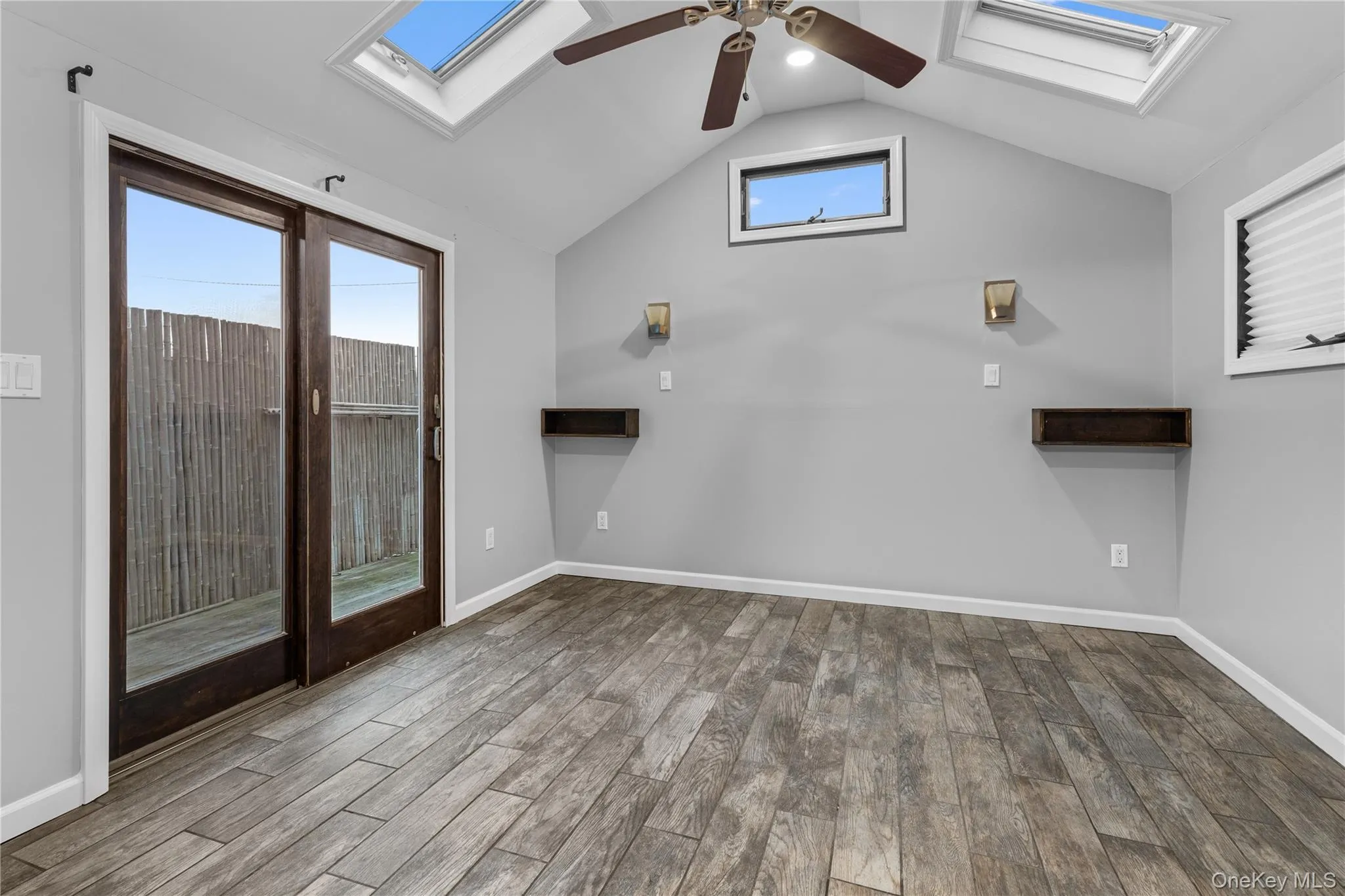 Unfurnished living room with a skylight, healthy amount of natural light, light wood finished floors, and vaulted ceiling Unfurnished living room with a skylight, healthy amount of natural light, light wood finished floors, and vaulted ceiling