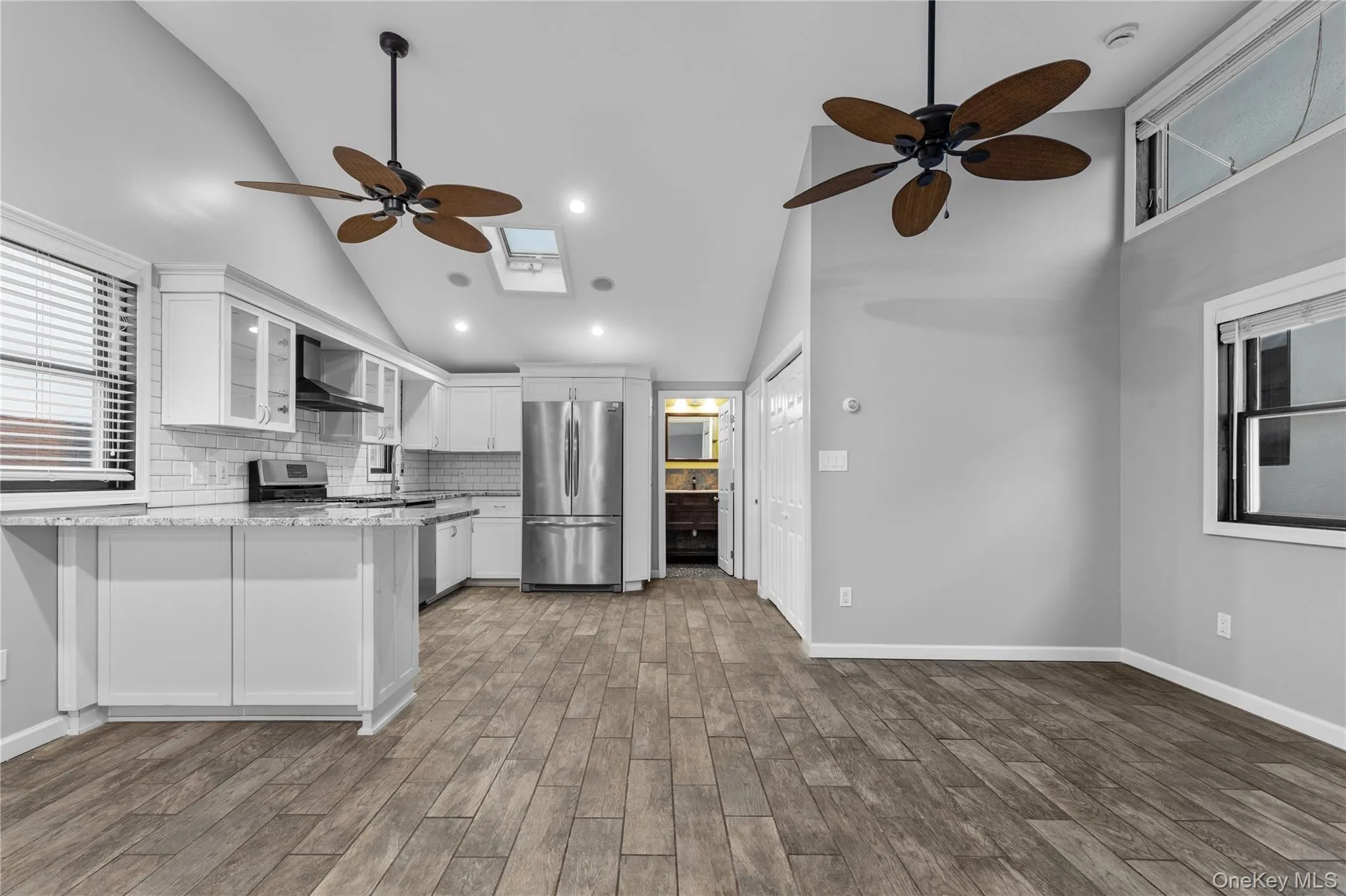 Kitchen with ceiling fan, white cabinets, appliances with stainless steel finishes, glass insert cabinets, and a peninsula Kitchen with ceiling fan, white cabinets, appliances with stainless steel finishes, glass insert cabinets, and a peninsula