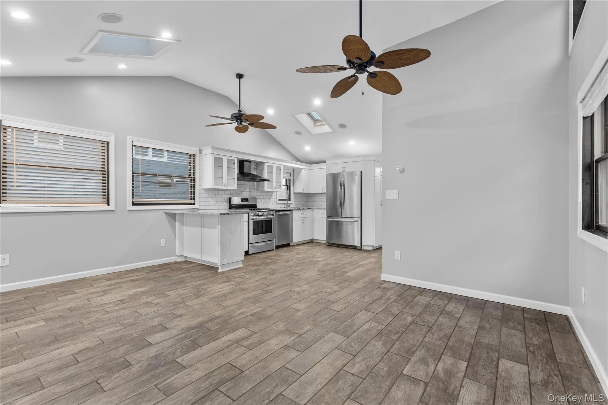 Kitchen with open floor plan, ceiling fan, glass insert cabinets, white cabinetry, and appliances with stainless steel finishes Kitchen with open floor plan, ceiling fan, glass insert cabinets, white cabinetry, and appliances with stainless steel finishes