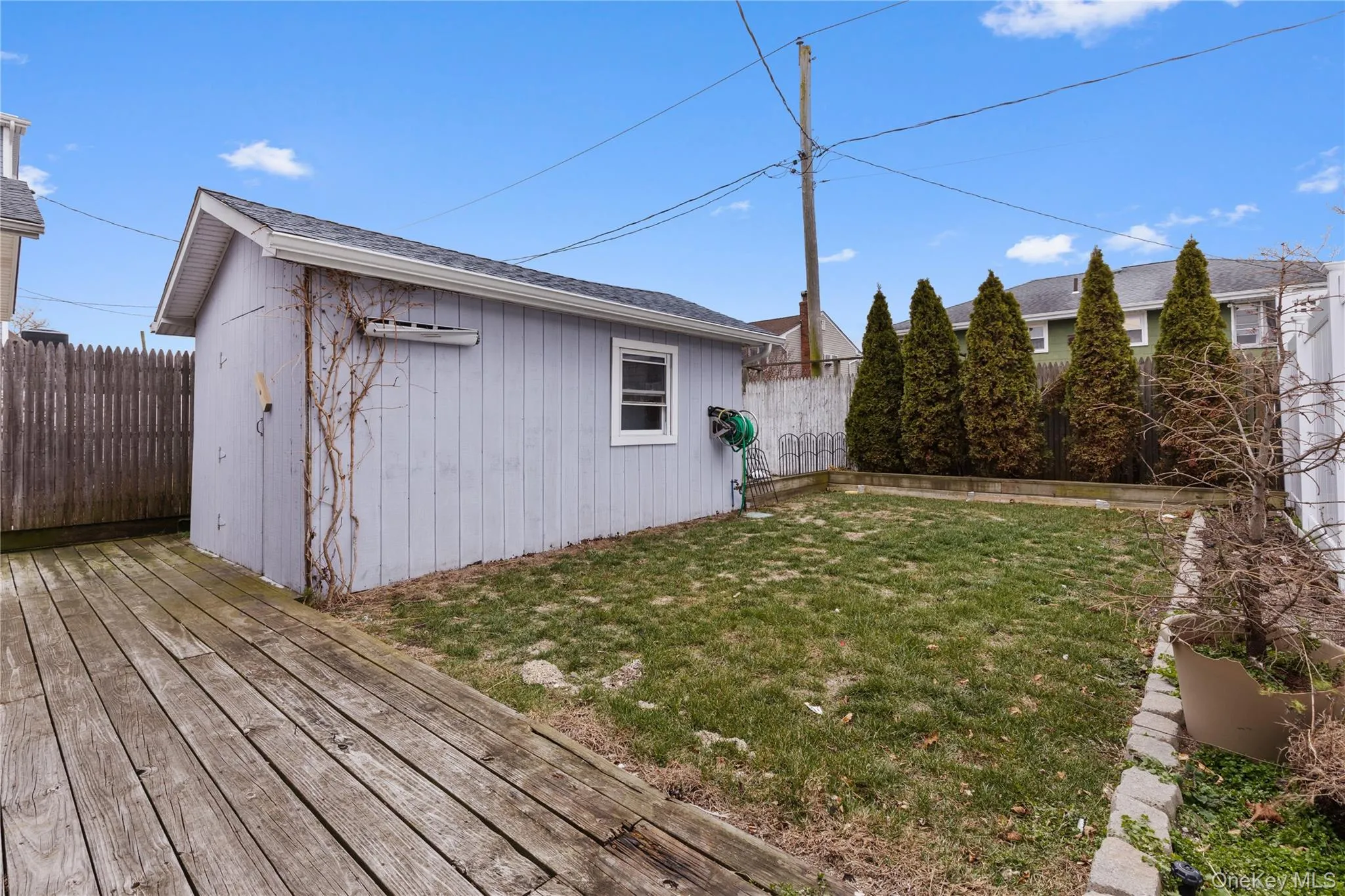 Fenced backyard featuring an outbuilding and a deck Fenced backyard featuring an outbuilding and a deck